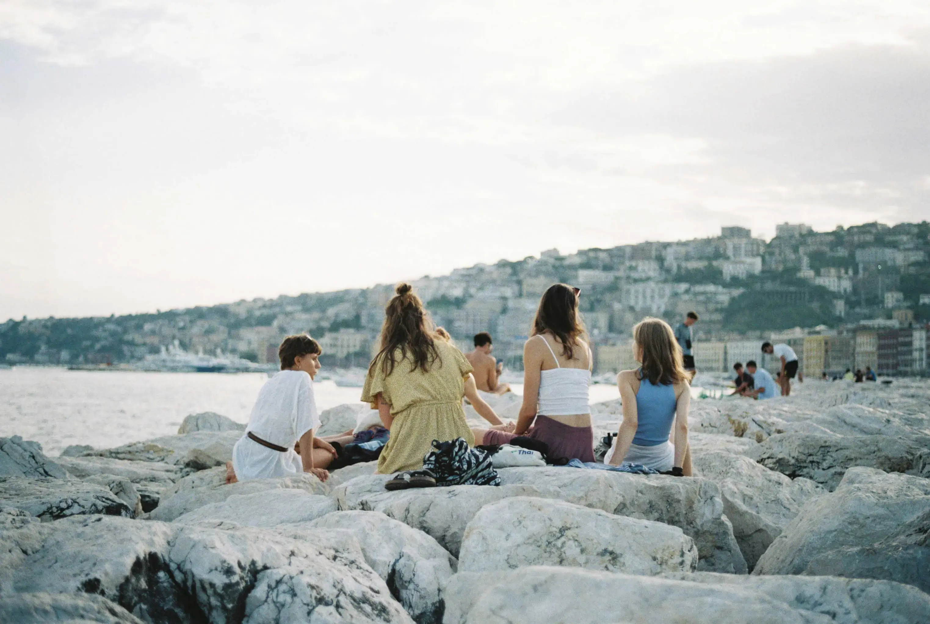 Six friends sitting on a wall by the ocean