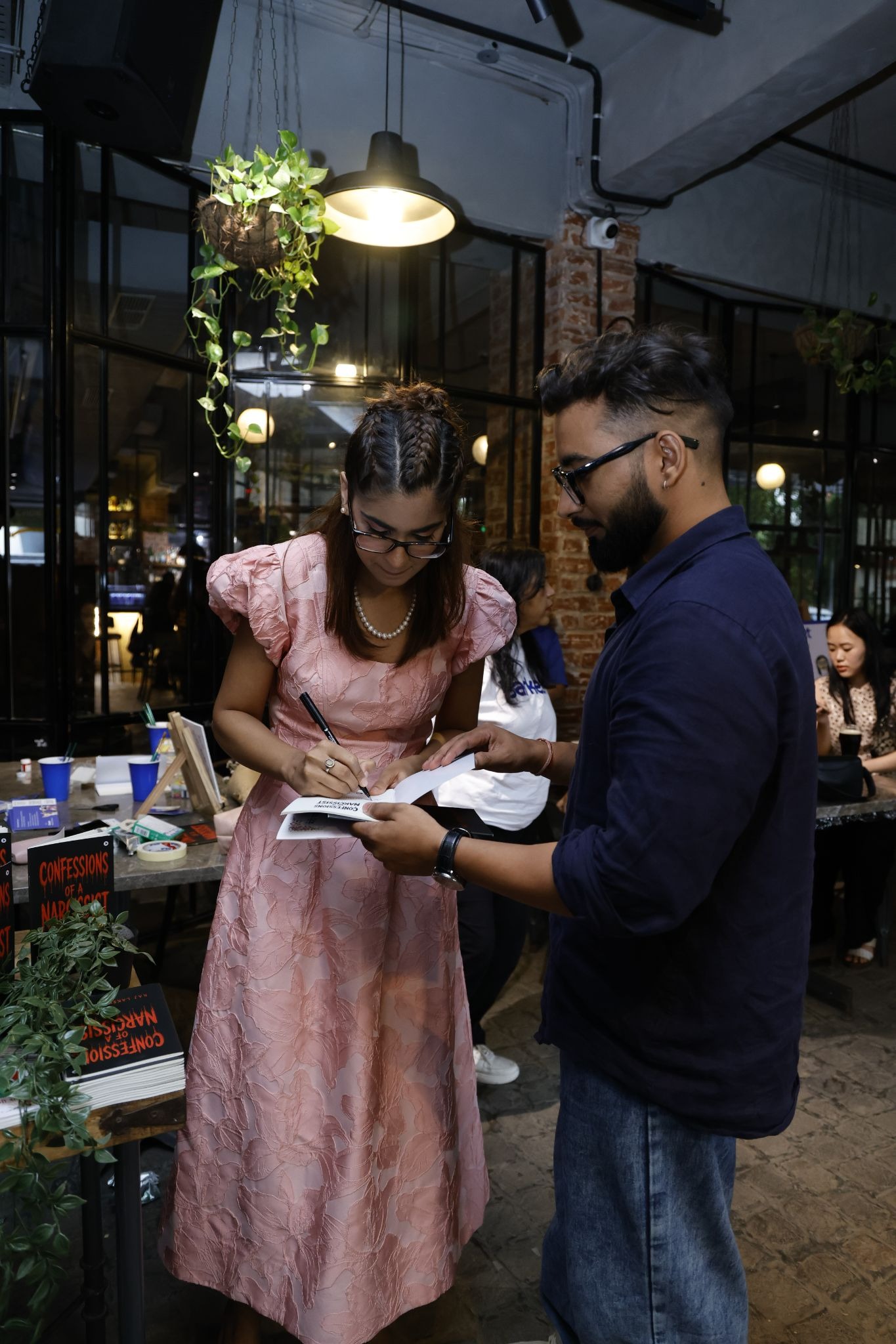 Raj Lakshmi Sharma signs a book for an attendee at an indoor event.
