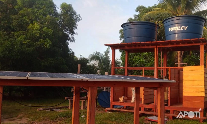 Foto na aldeia Huni Kuin com caixa dagua e placas solares feitas pela APOTI