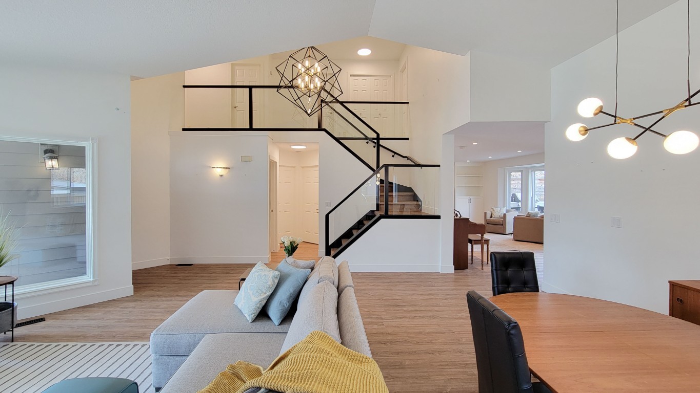 Image of Modern living room with staircase, sofa, dining table, and pendant lights, showcasing KHD Homes design-build expertise.