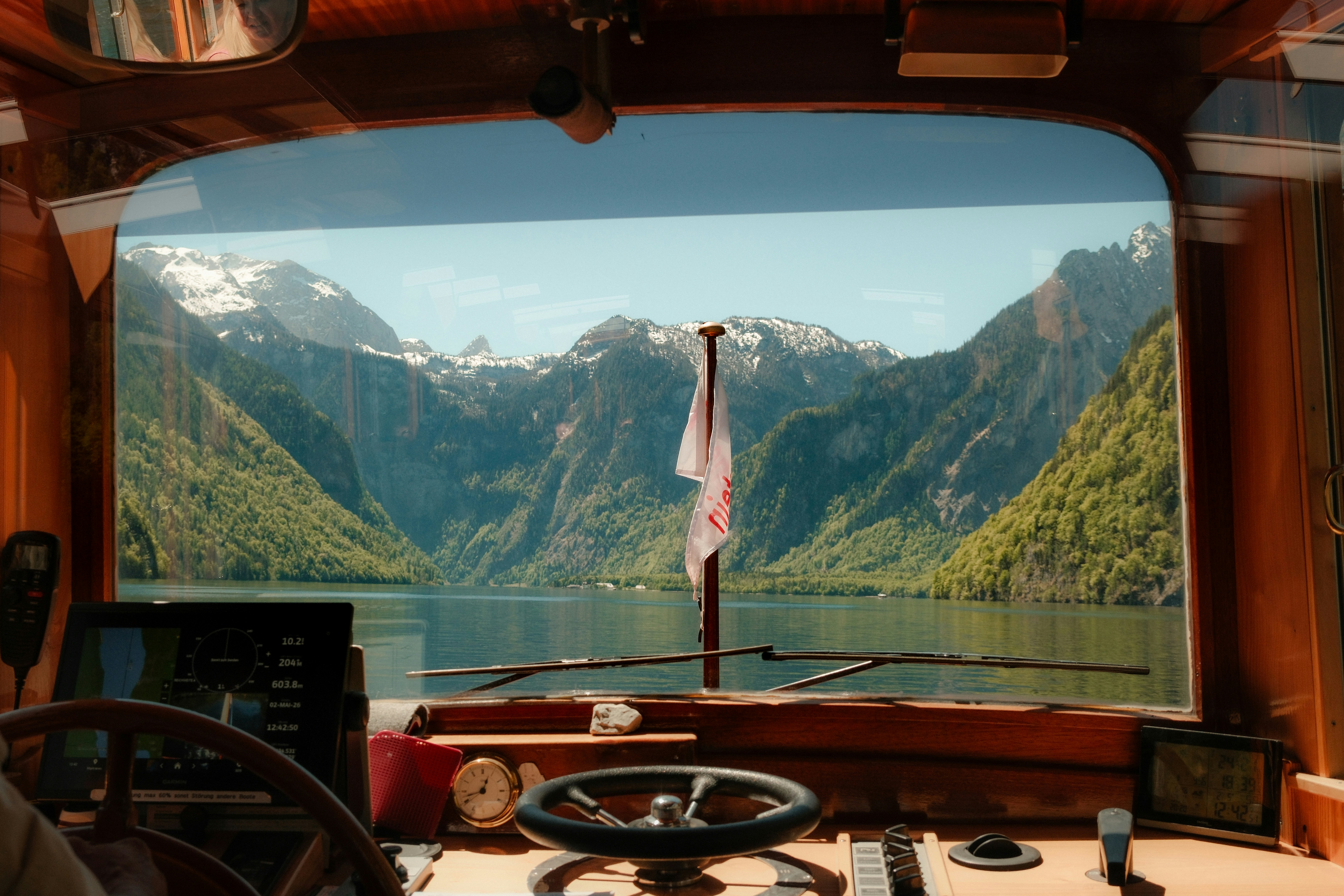 View from a boat cockpit of a serene mountain lake.