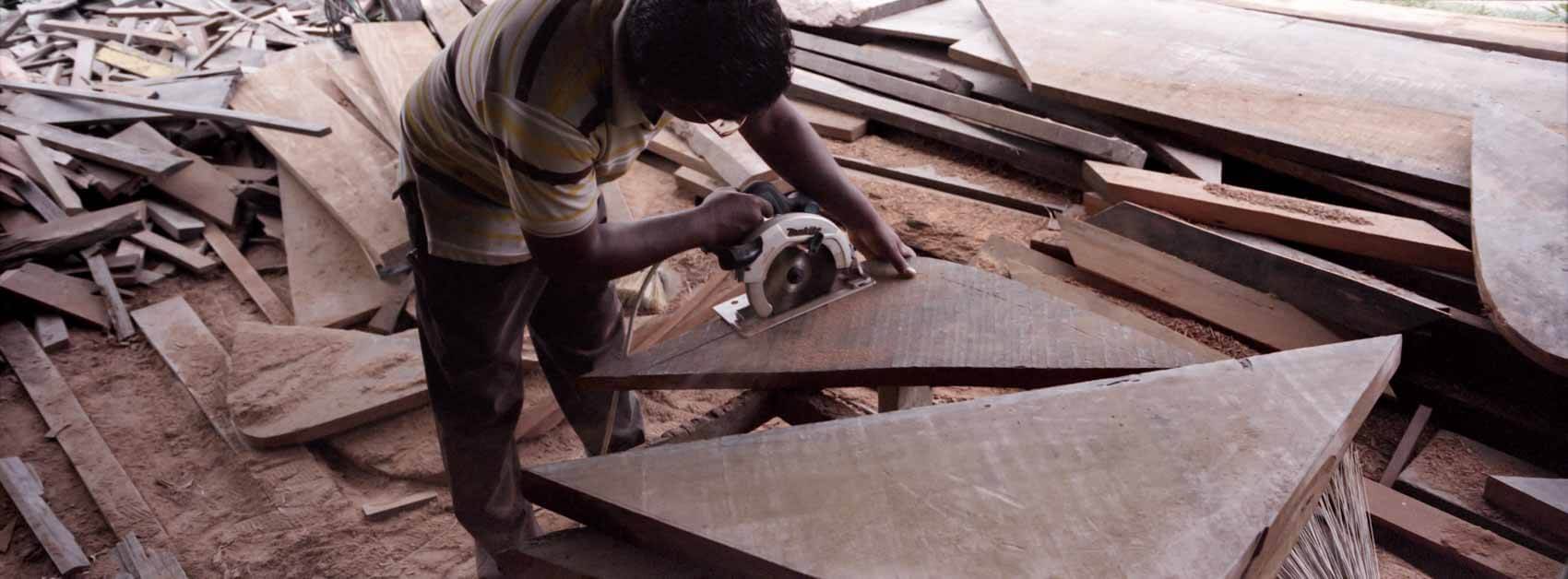 Traditional wooden boat builder in Suriname working inside a workshop, framed by wood, soft directional light shaping the scene, photographed on a Hasselblad Xpan and Kodak Portra. 