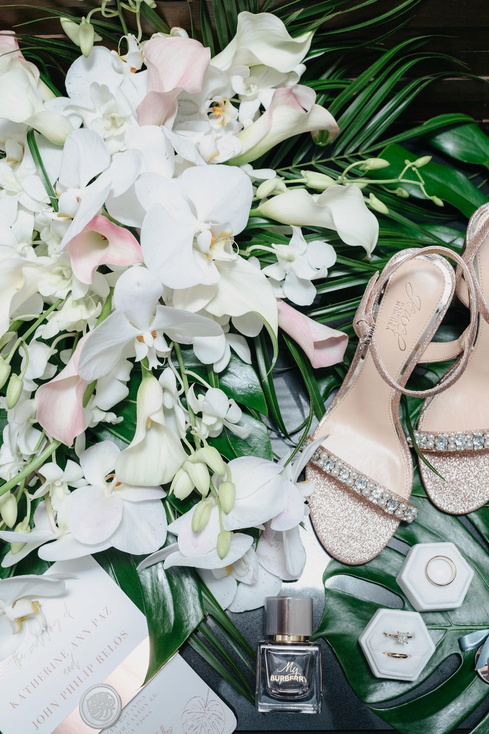 Flat lay wedding details with bouquet, rings, and sparkling bridal heels