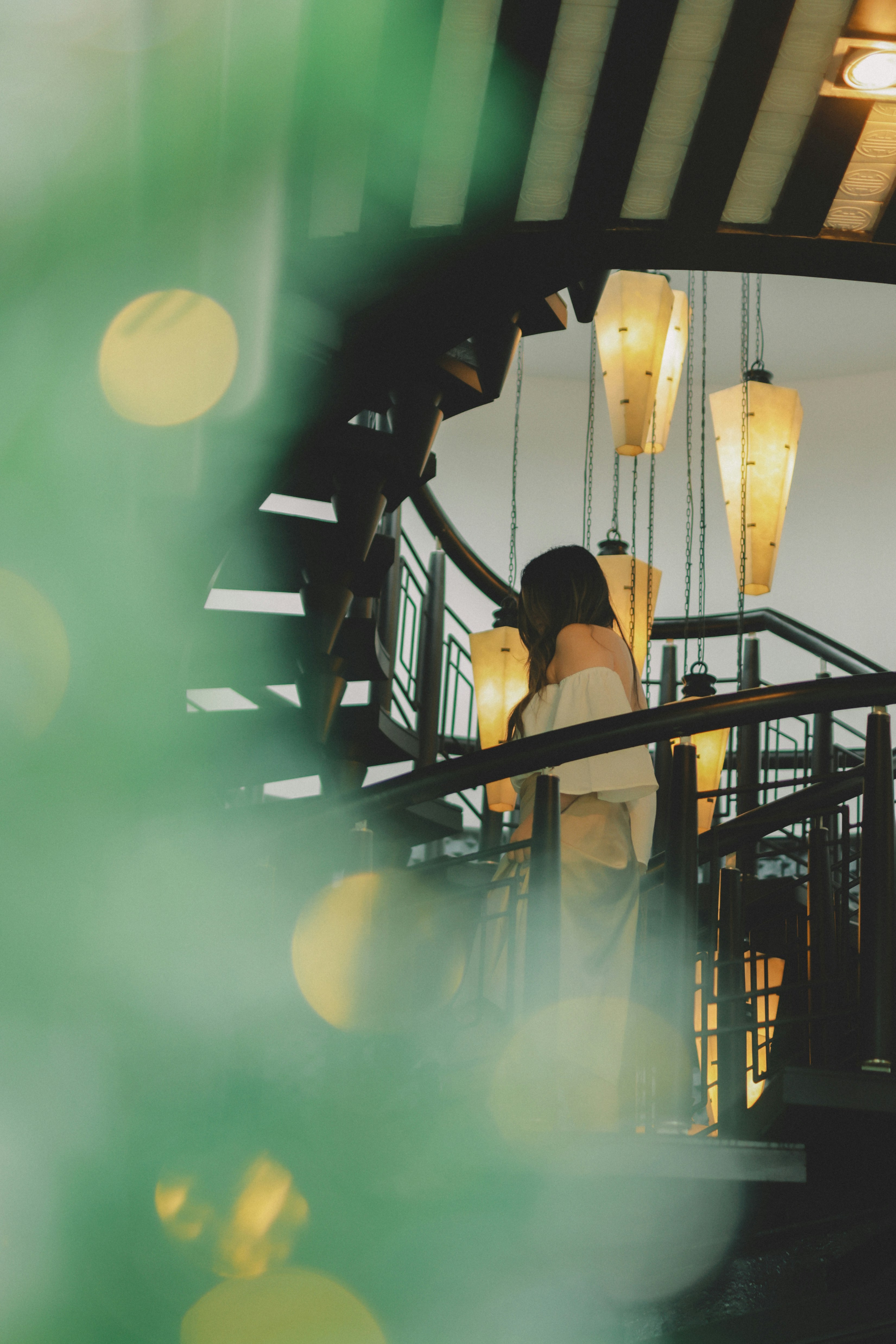 Woman on a spiral staircase with hanging lamps