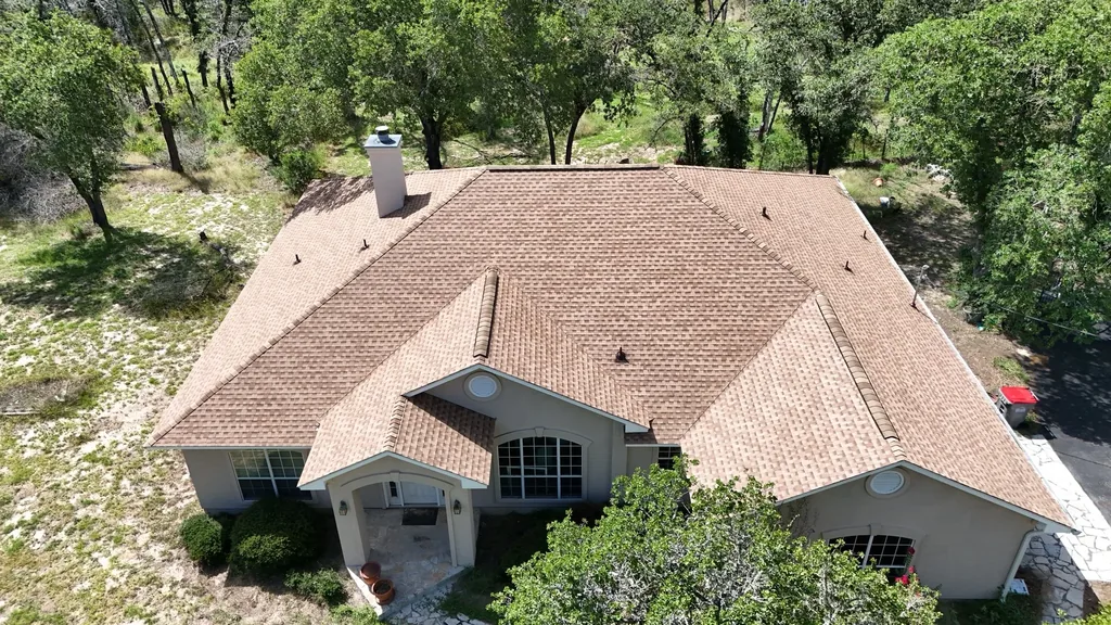 Finished Floresville shingle roof viewed from above the front gables, with the chimney and intersecting roof sections visible.