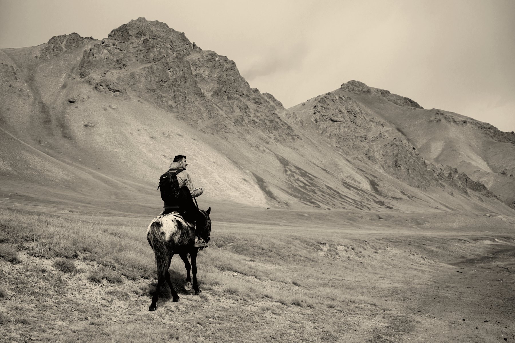 A rider on horseback crossing dry hills