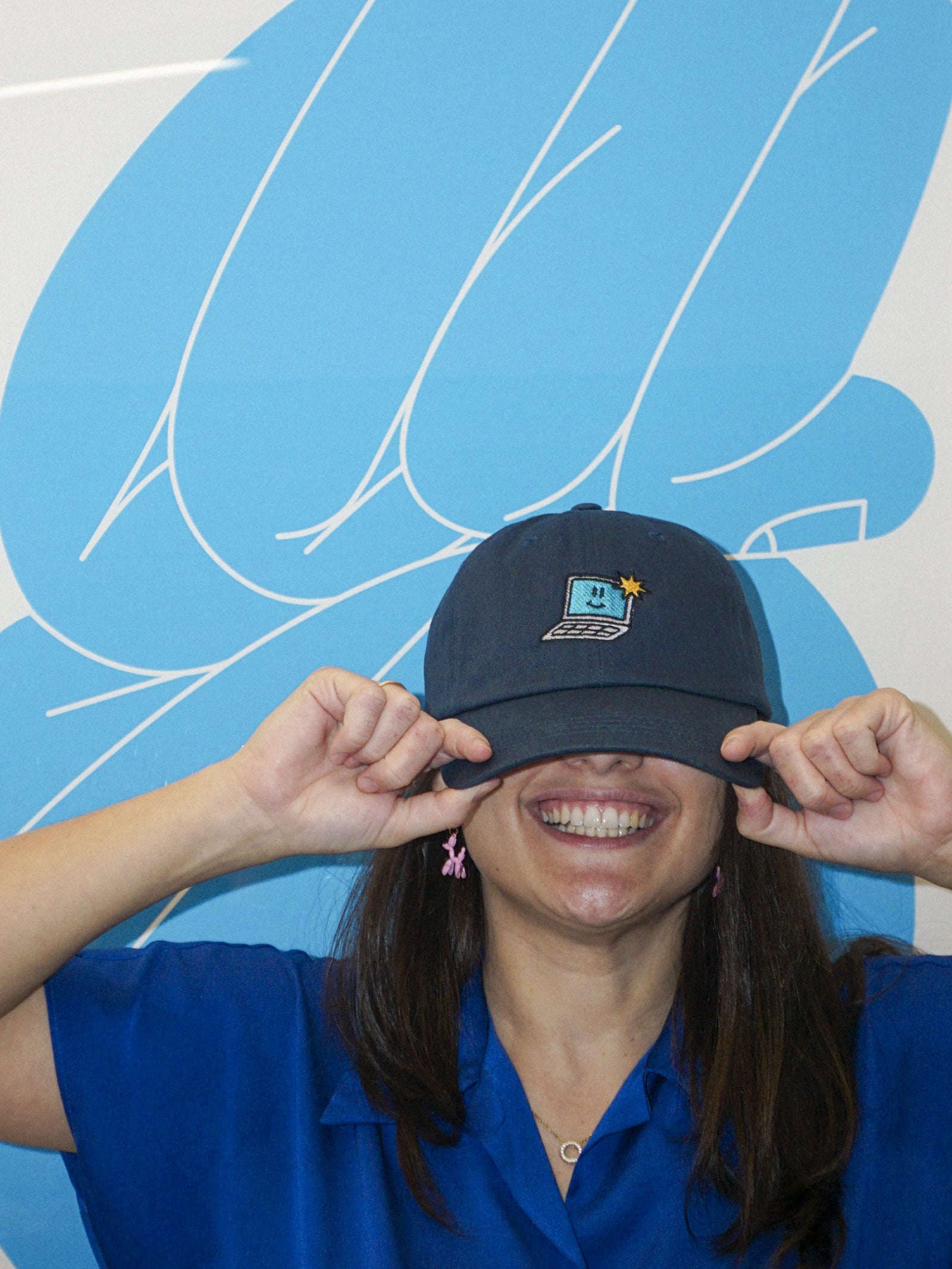 Person wearing a blue cap with a logo against a blue background