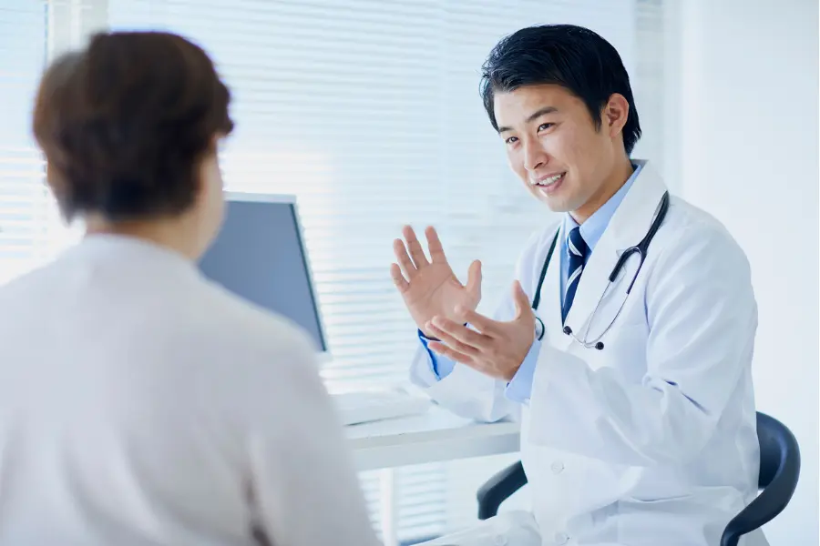Clinical decision software helping a doctor explain a diagnosis to a patient in a bright medical office.