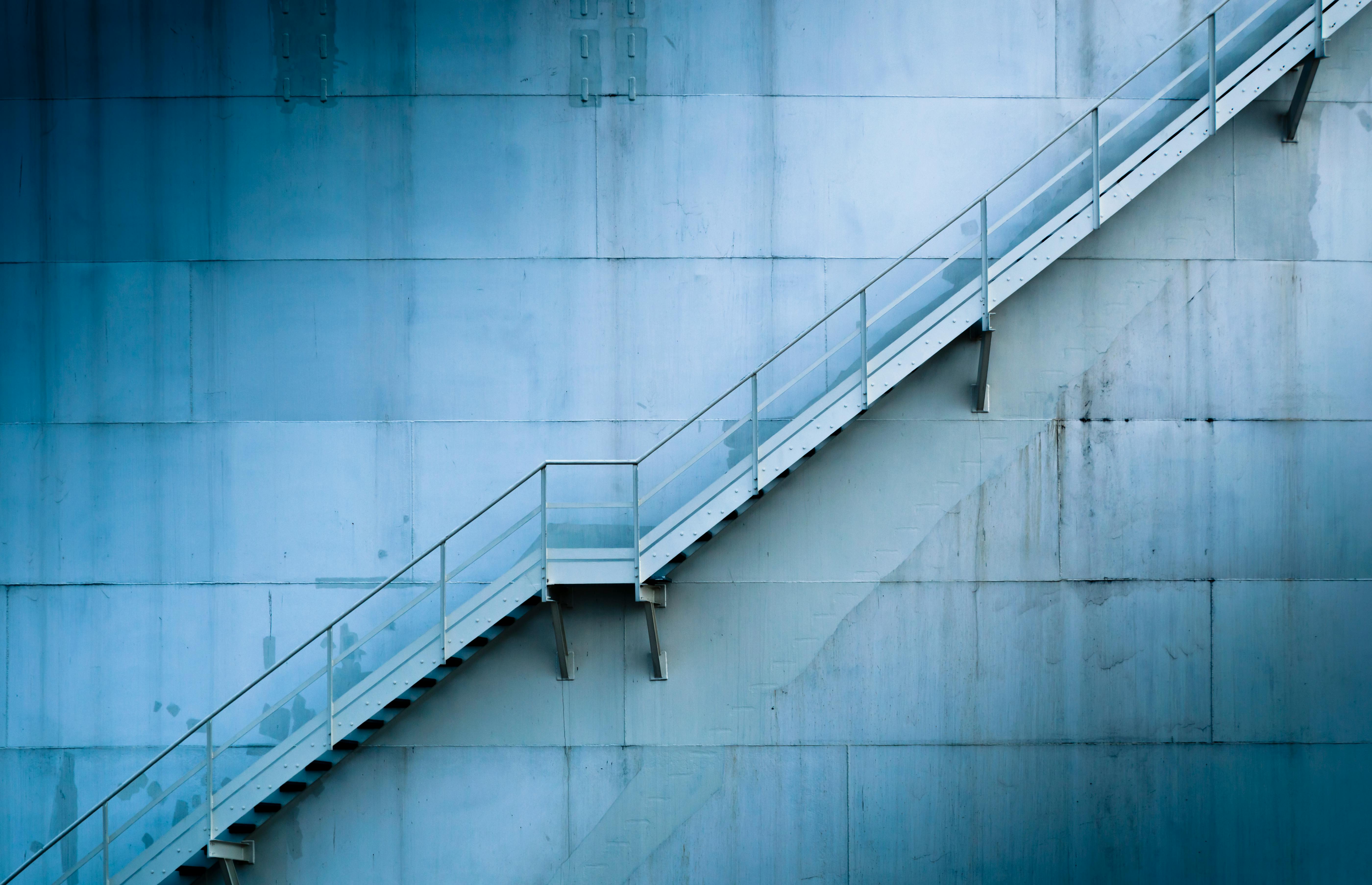 Metal staircase ascending along blue industrial wall