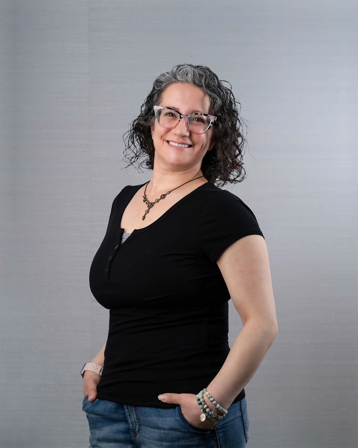 Woman with grey curly hair, smiling brightly.