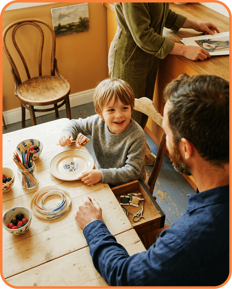 Child laughing at a kitchen table with a parent
