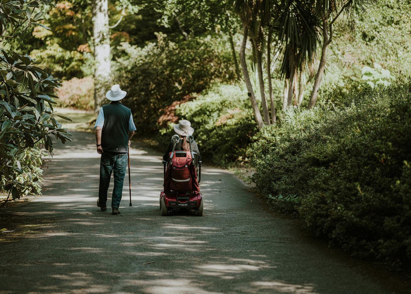Two people with parkinsons disease traversing down a shaded path