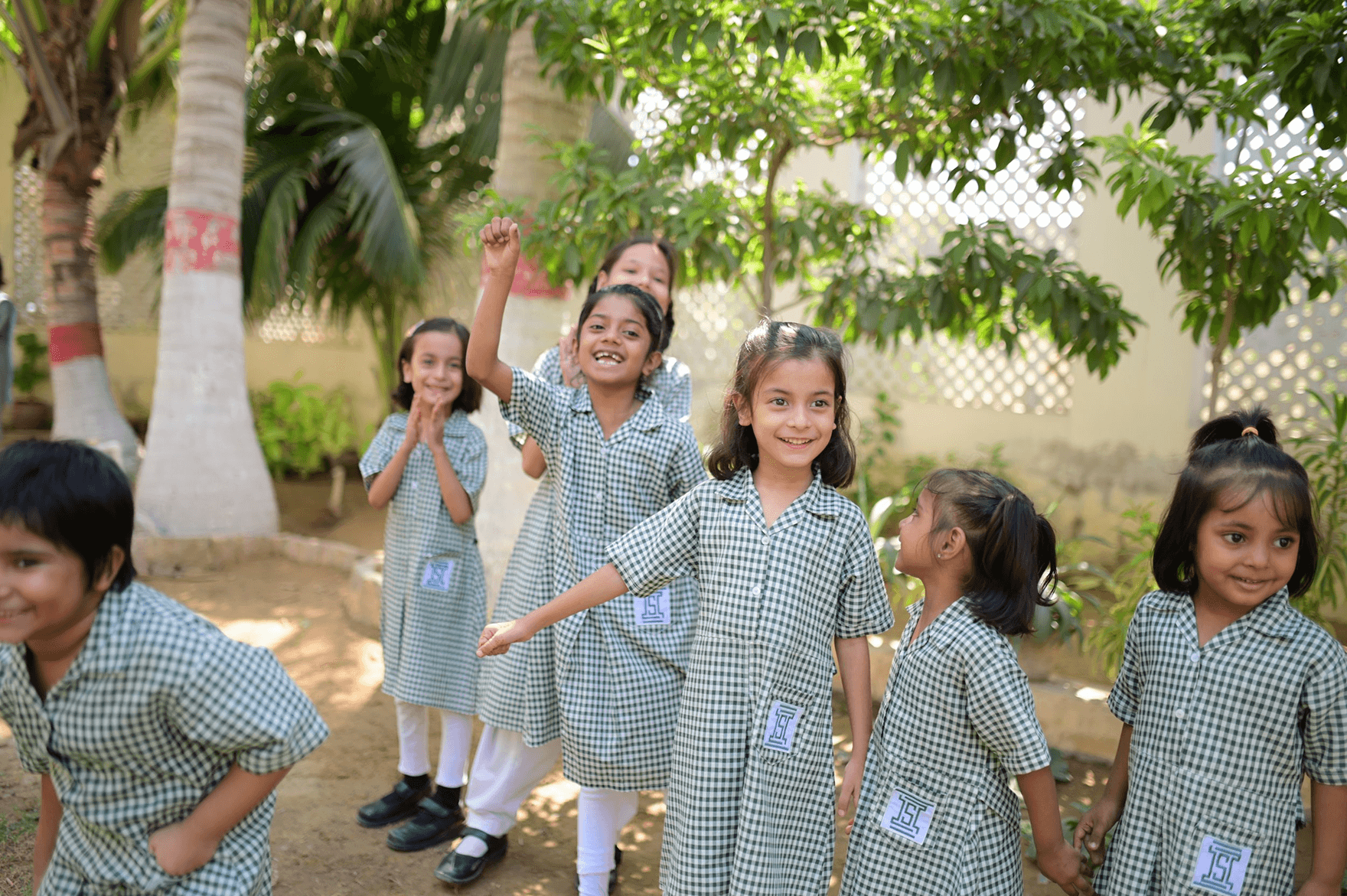 A teacher and two schoolgirls are examining a globe together in a classroom