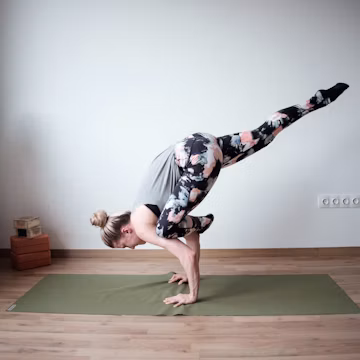 a woman doing a handstand on a yoga mat
