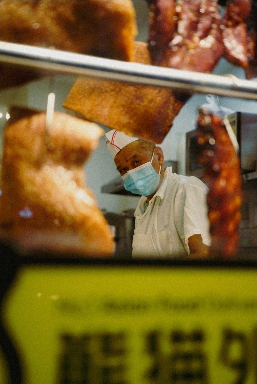 Man preparing Chinese take-out with roast ducks hanging in foreground