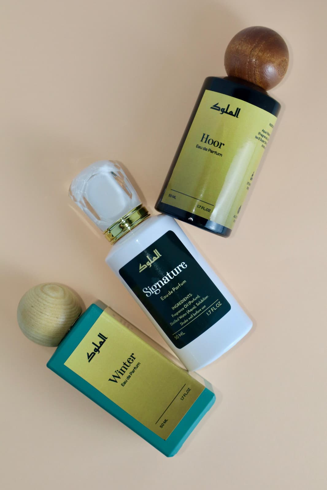 Flat lay of Al-Mulook Signature perfume bottle with packaging and branded inserts.