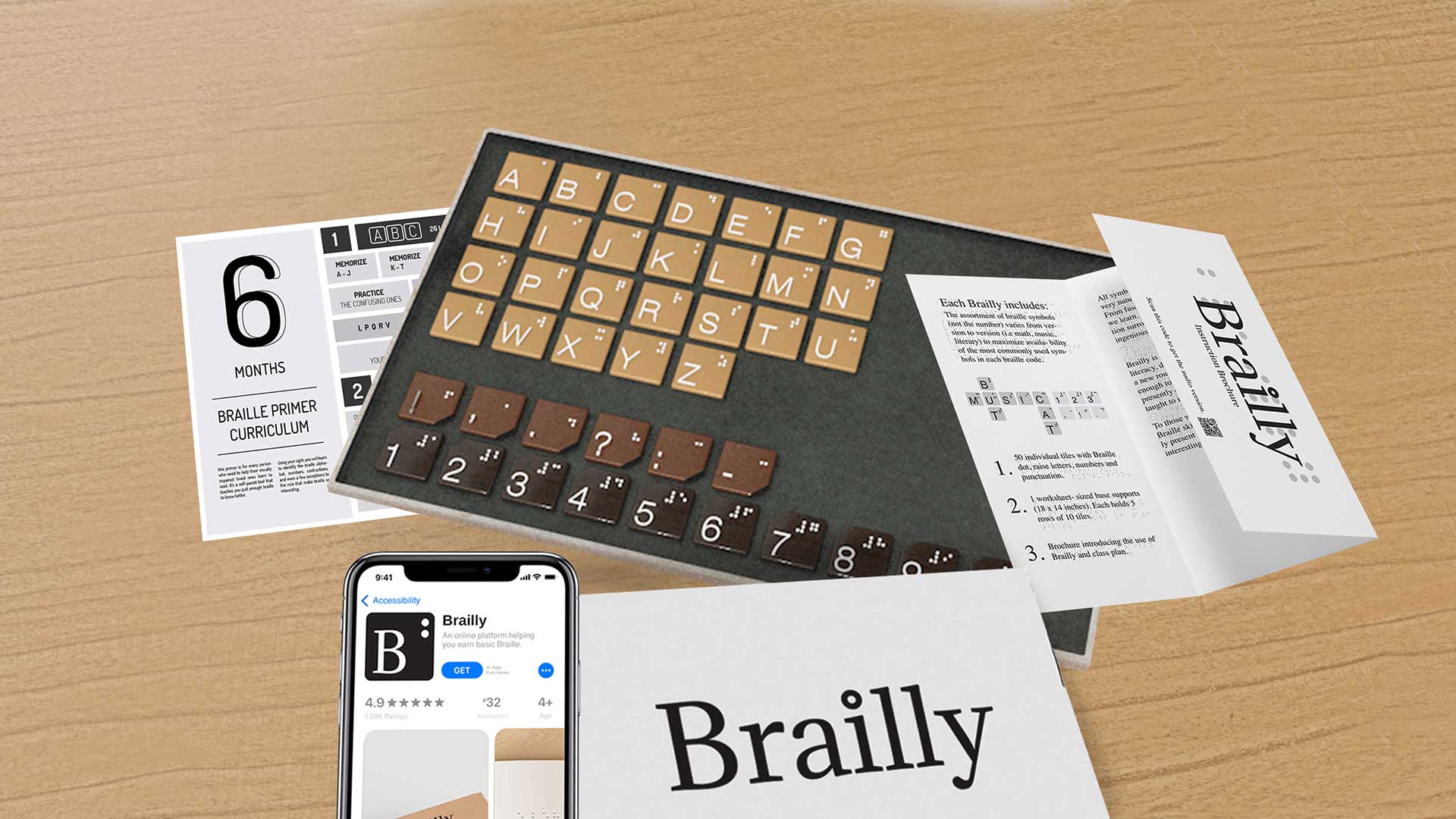 A Brailly keyboard with brown keys and black lettering rests on a light brown wooden surface. A smartphone displaying the Brailly app interface is positioned near the keyboard. A white sheet with the Brailly logo is partially visible beneath the keyboard. A sheet labeled “6 MONTHS” and a Braille primer curriculum sheet are also present on the surface. The scene is illuminated by natural daylight.
