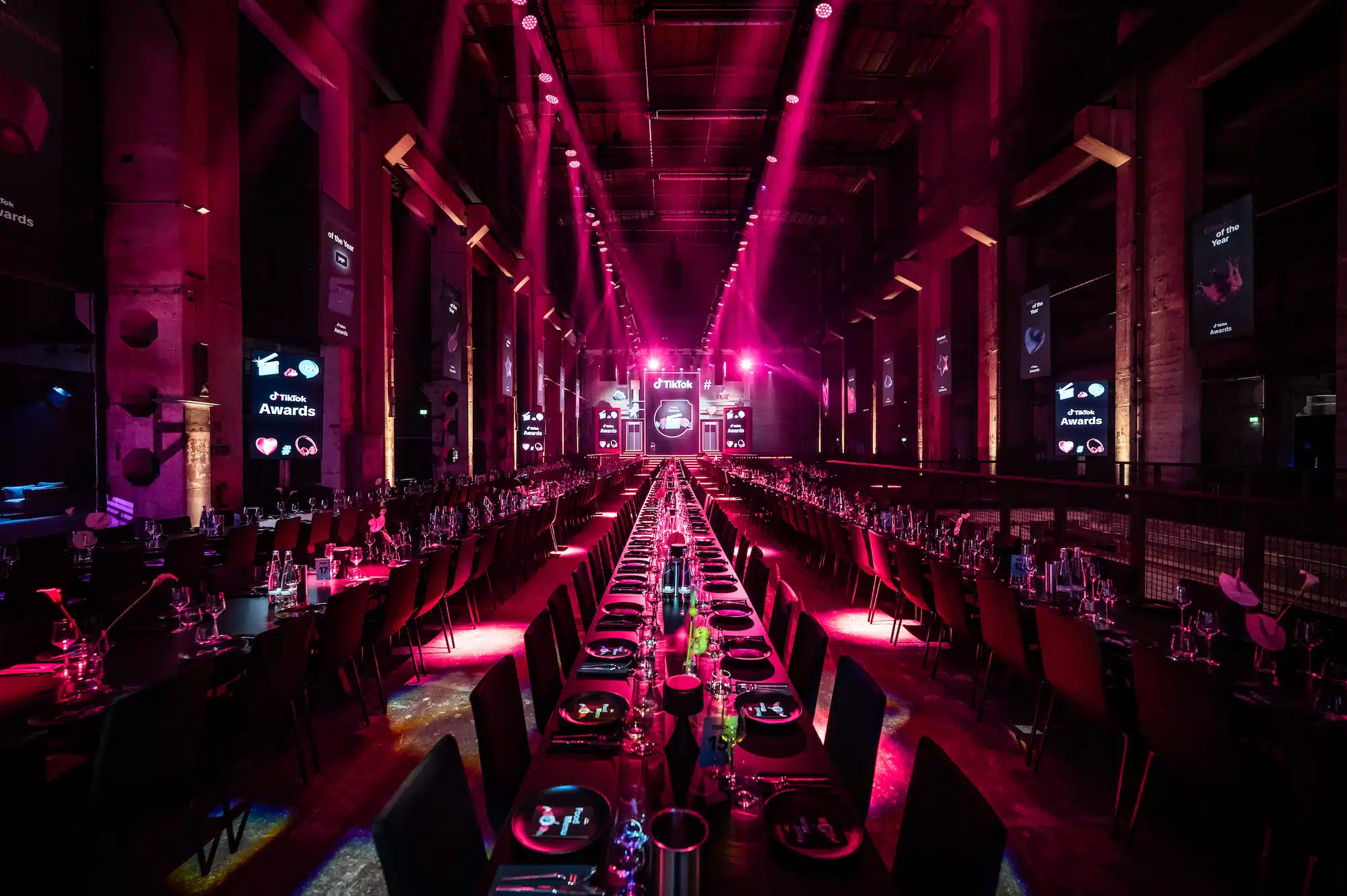 TikTok Awards – overview of the gala dinner hall with long tables, pink ambient lighting and TikTok Awards screens