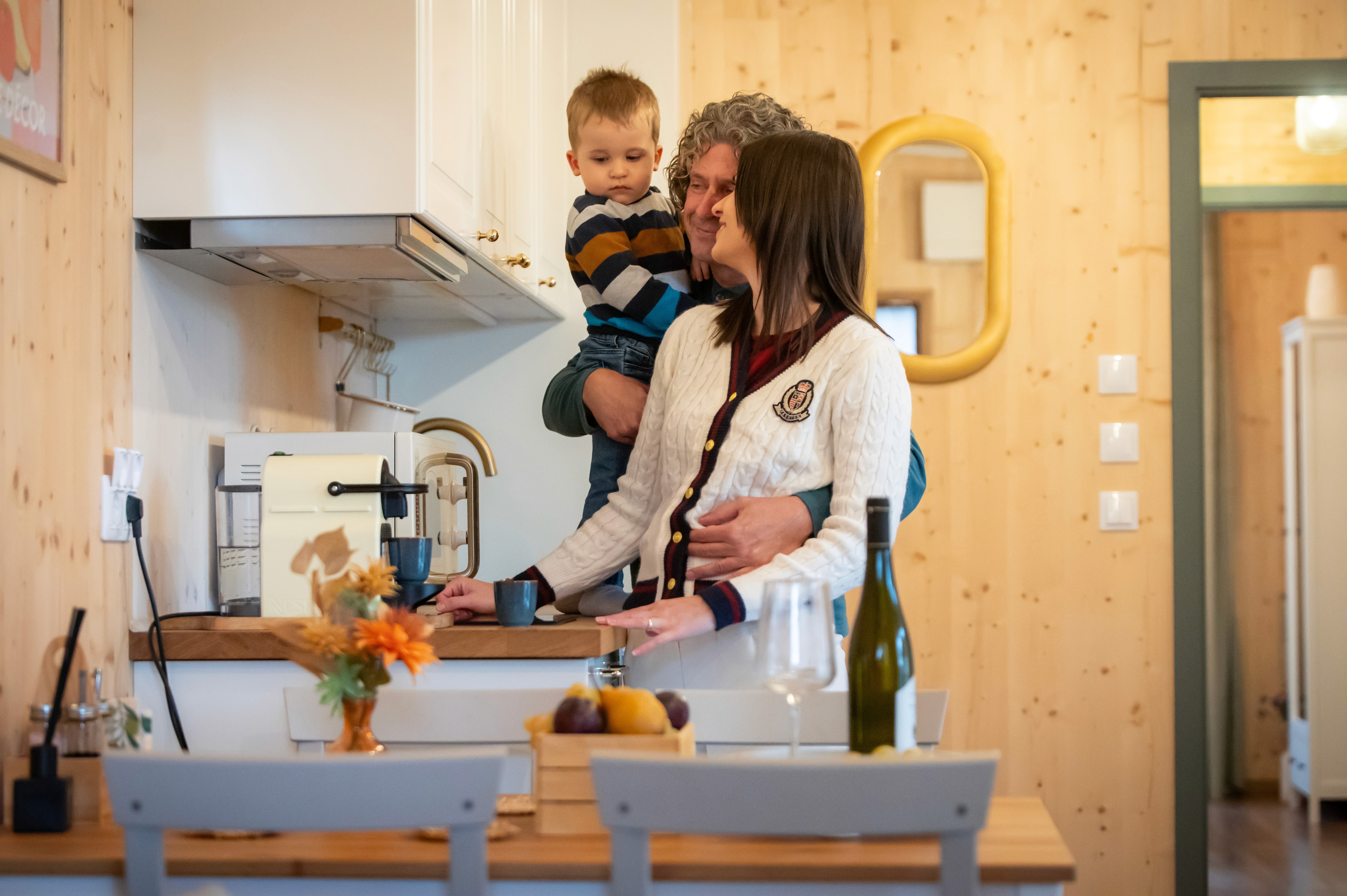 Modern konyhai környezetben látható ülelkező család.