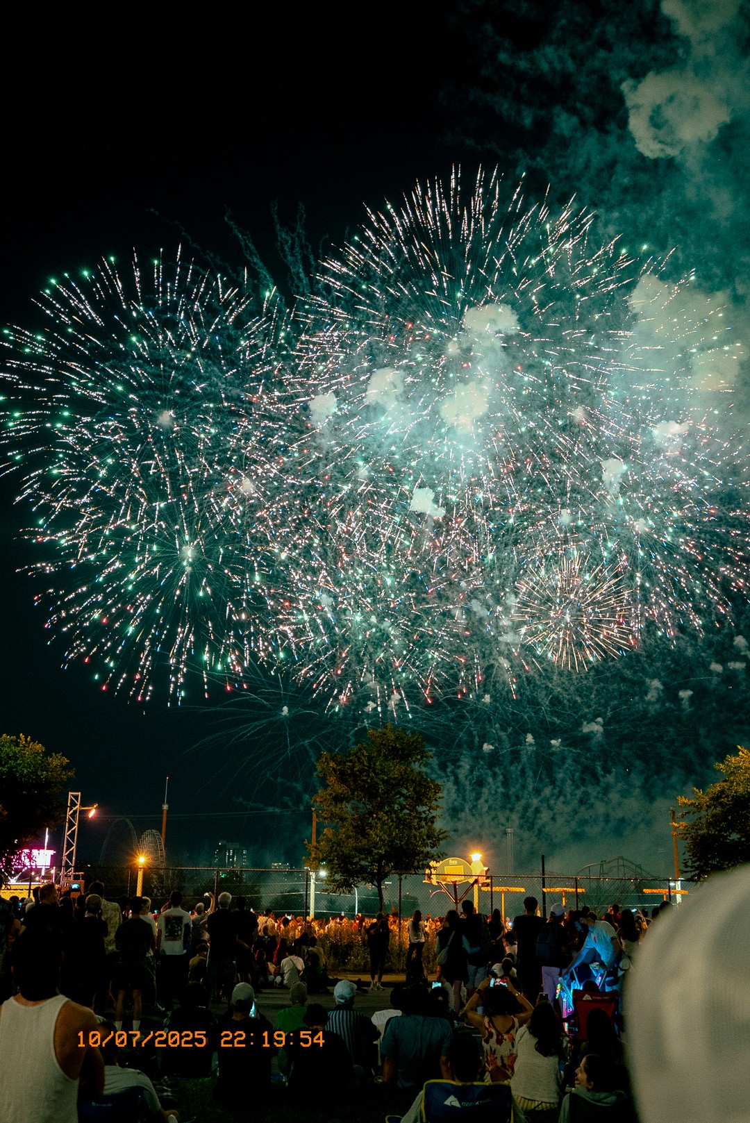 Feu d’artifice spectaculaire au-dessus d’une foule à Montréal en soirée d’été.