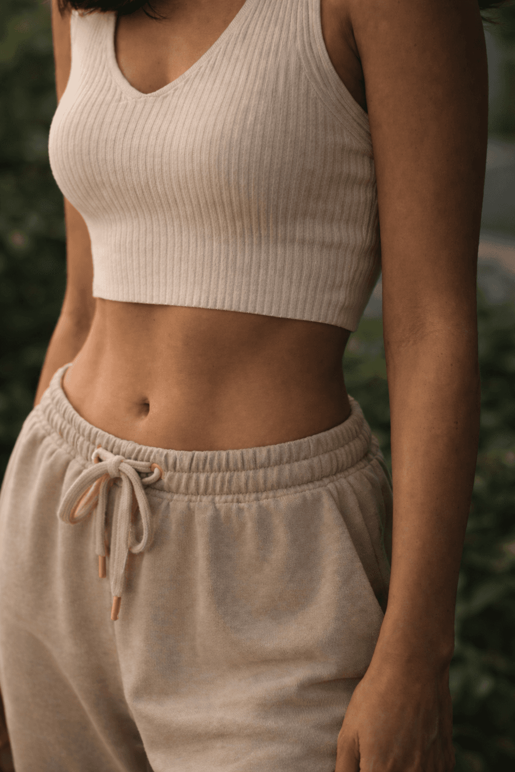 Smiling young woman with long hair standing against a dark green background, holding a finger to her chin.