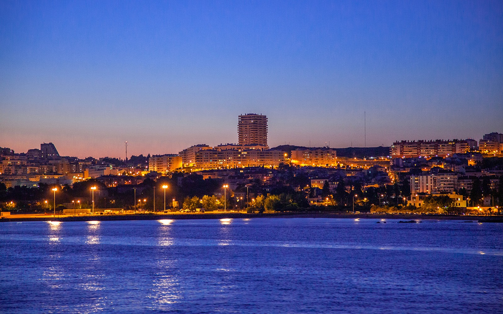 Paisagem urbana de Lisboa ao anoitecer vista a partir de um cruzeiro noturno no Rio Tejo.