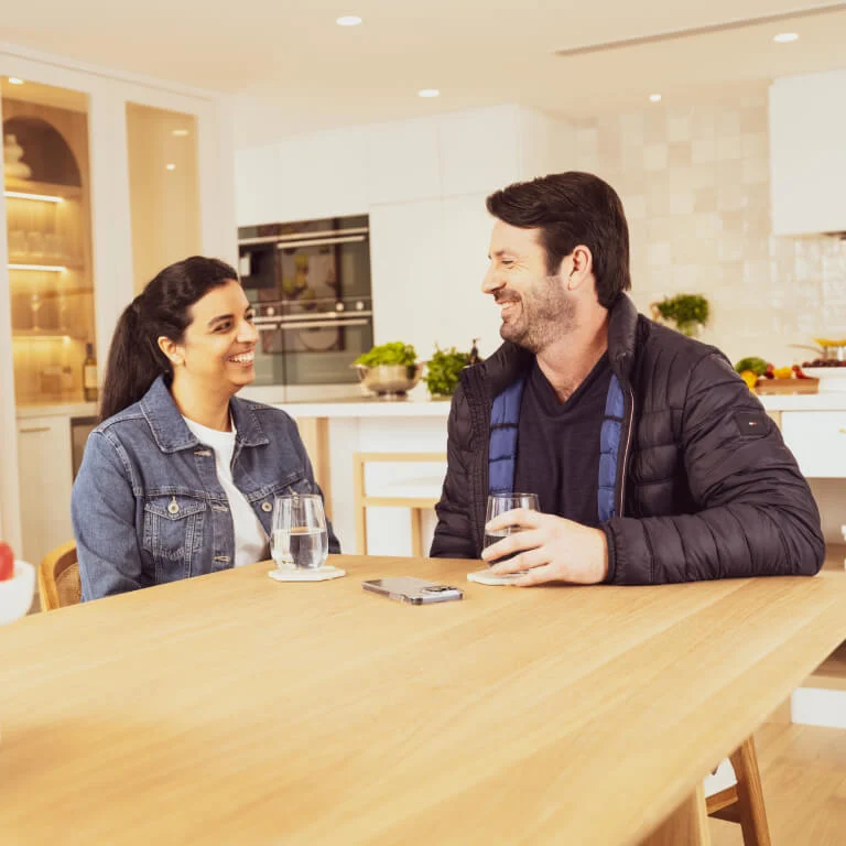 A couple similing at each other at a dining room table