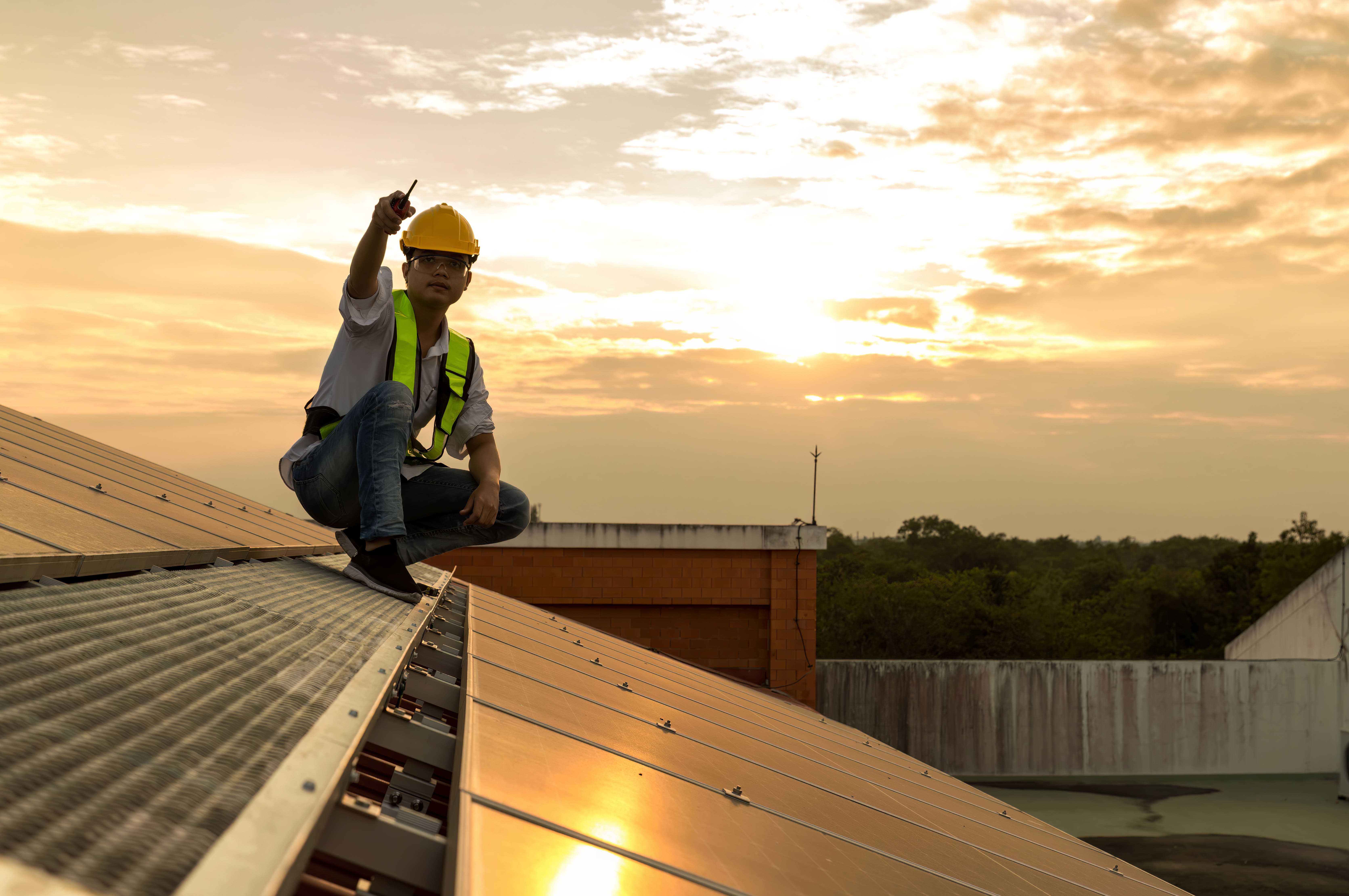 Techniker auf einem Dach mit Photovoltaikanlage bei Sonnenuntergang, zeigt Engagement für erneuerbare Energien – Solartechnik Nordwest.
