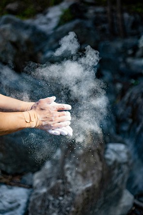 Mit Chalk eingepuderte Hände vor Fels – Griffkraft- und Technikvorbereitung fürs Bouldern und Klettern.