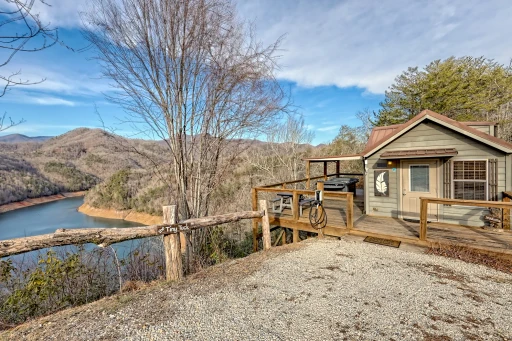 Tiny Tuck cabin on its ridge-top deck above a bend of Fontana Lake, with the Smoky Mountains behind