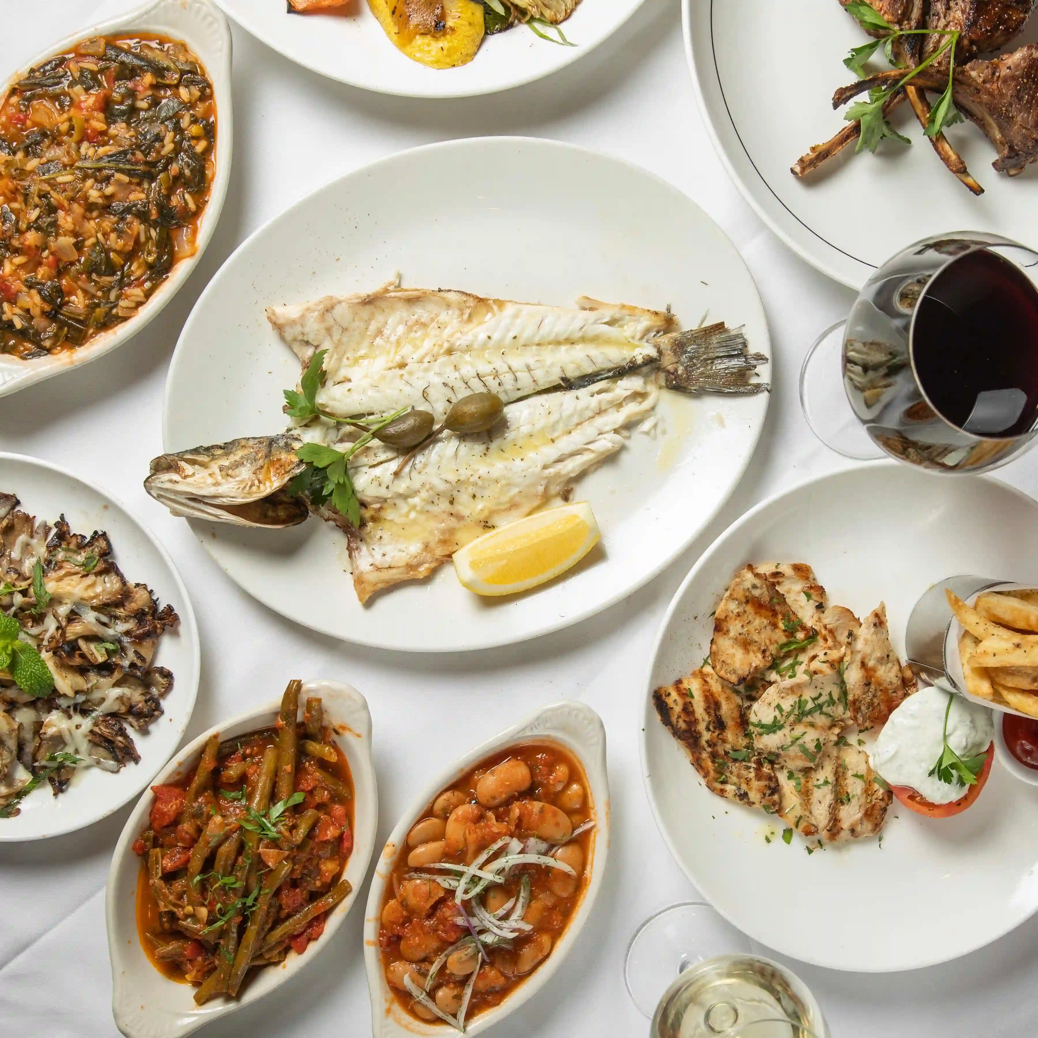 A variety of seafood dishes served on white plates, featuring fish, shellfish, and flavorful sides.