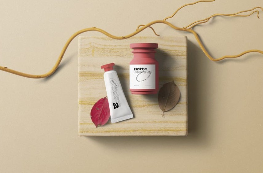 Pink jar and white tube on a marbled board, from above