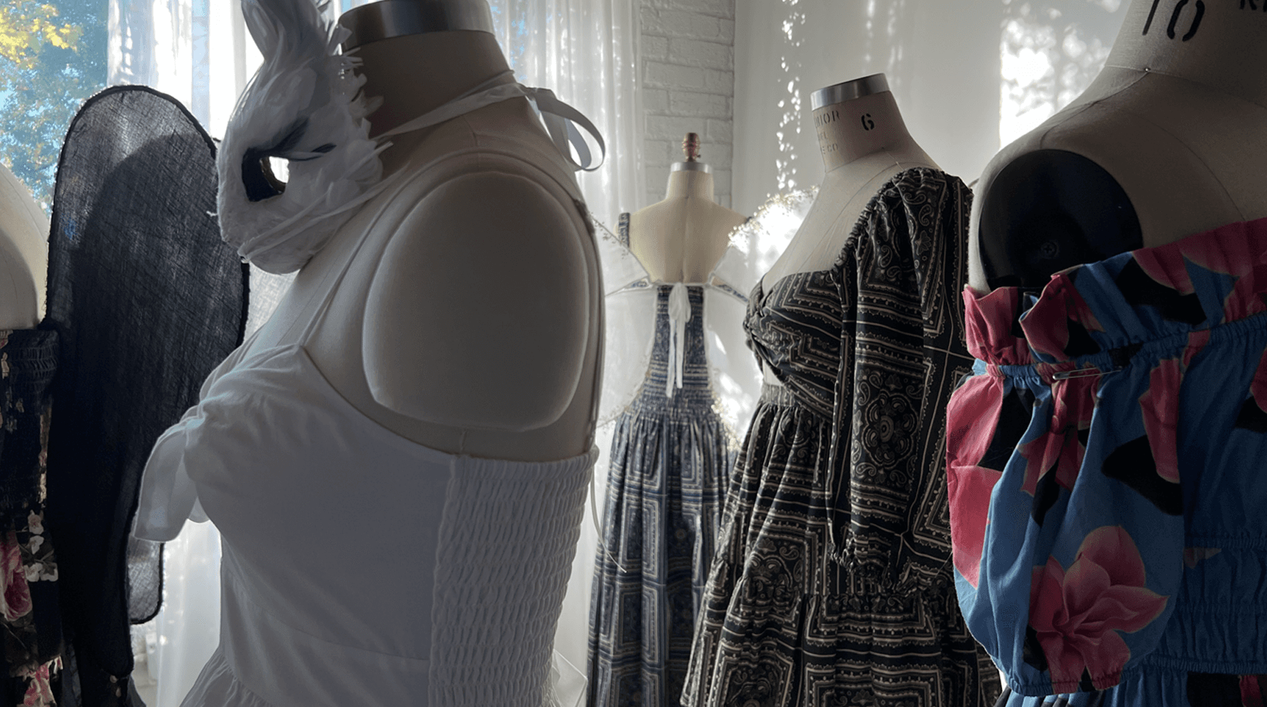 A row of different colored dresses in a studio.