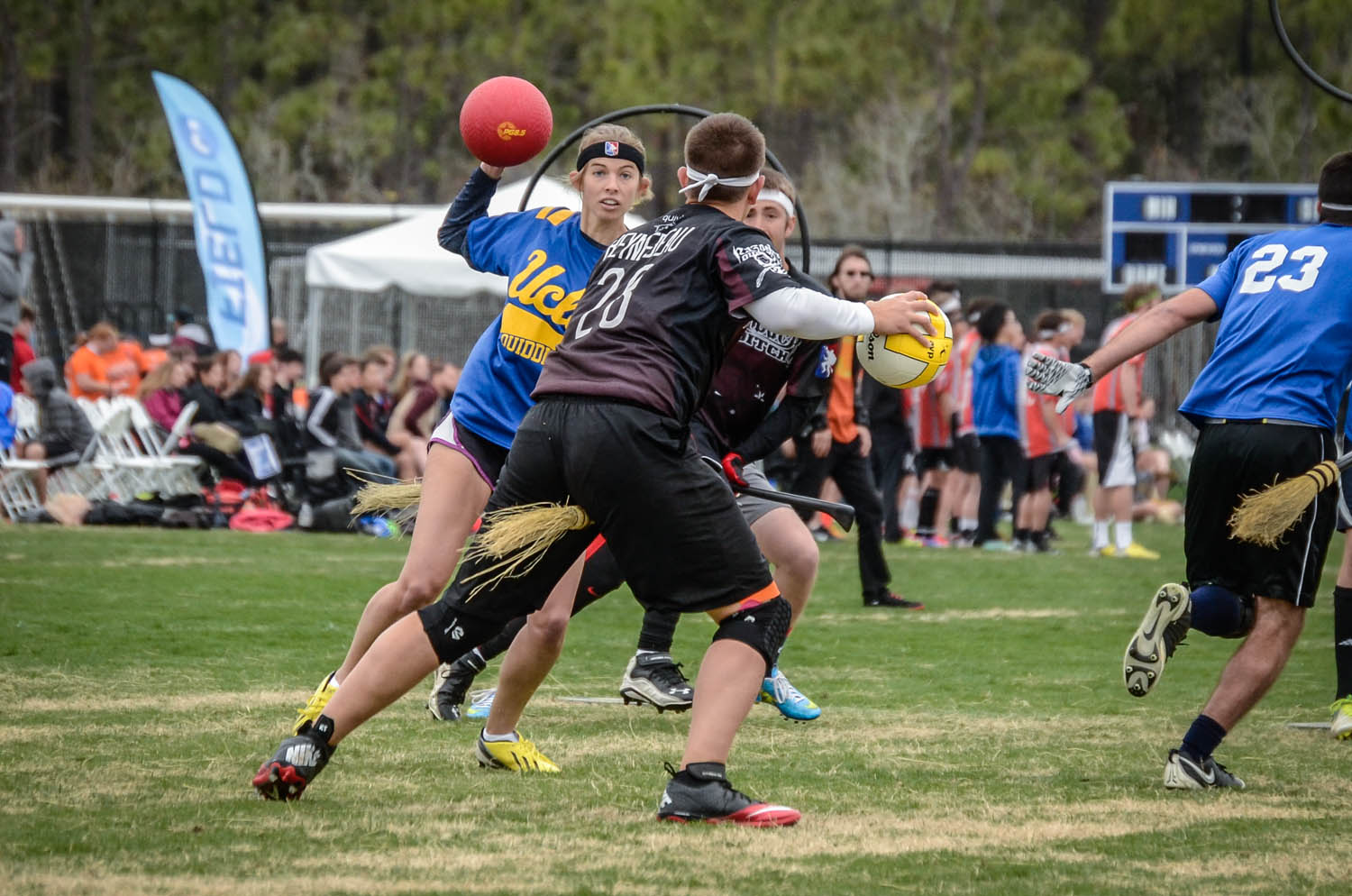 A UCLA Quidditch beater raises a dodgeball toward a ball-carrying chaser