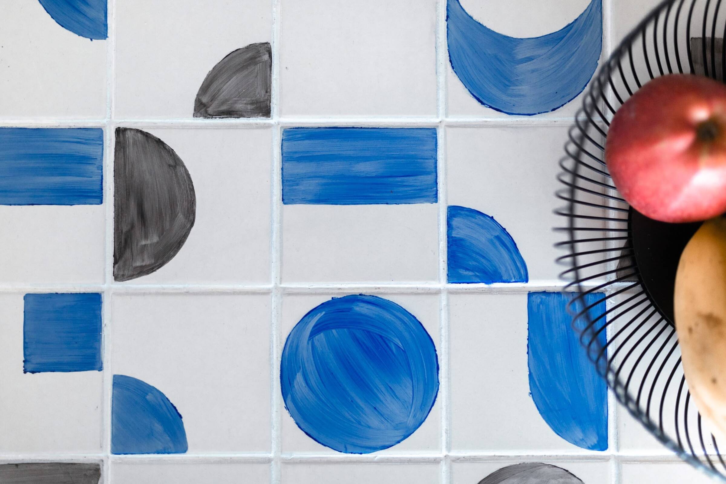 Close-up of bespoke centre table with hand-painted tiles in black, beige, and blue, a bold studio statement