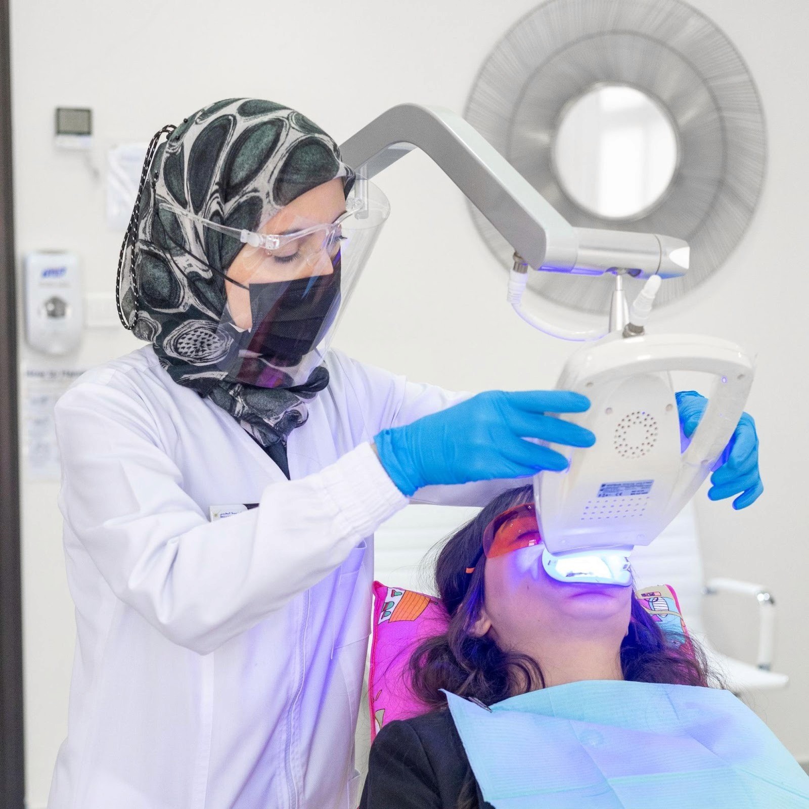 A cosmetic dentist at Bella Medical Center wearing a mask and scrubs while performing a Hollywood Smile treatment.
