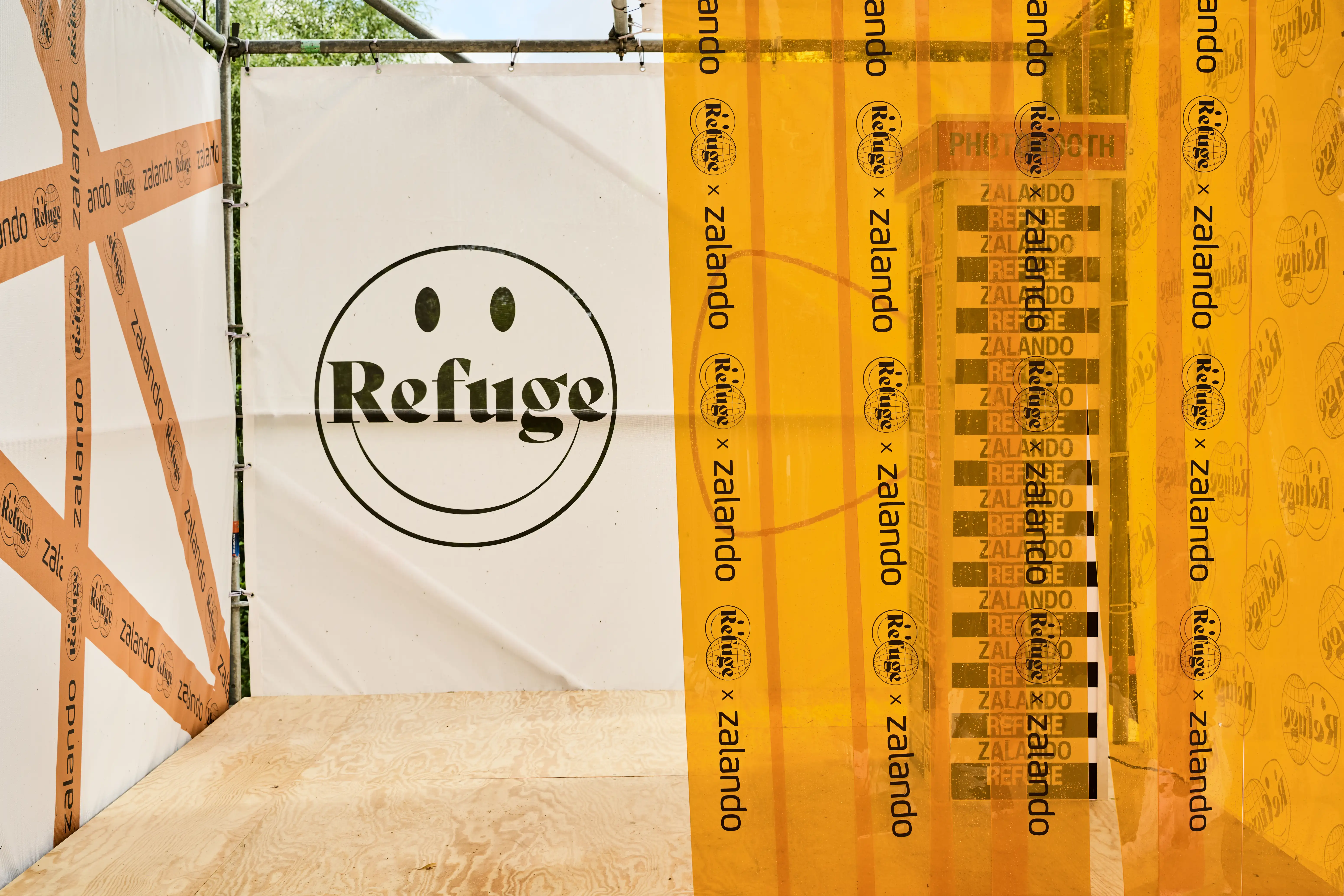 Refuge smiley banner next to orange Zalando x Refuge curtain on the festival photo booth.