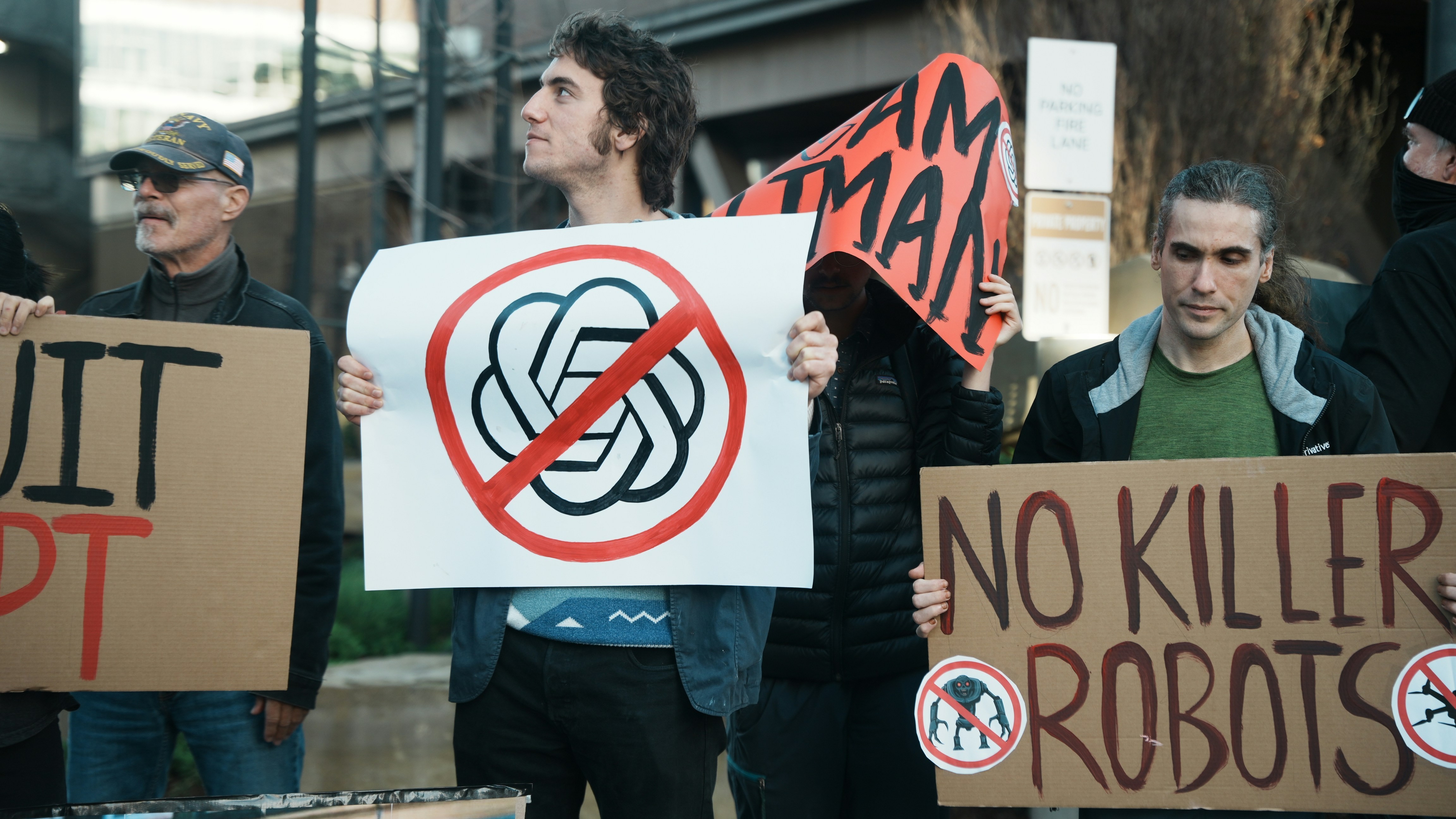 Protestors hold signs against AI and robots.