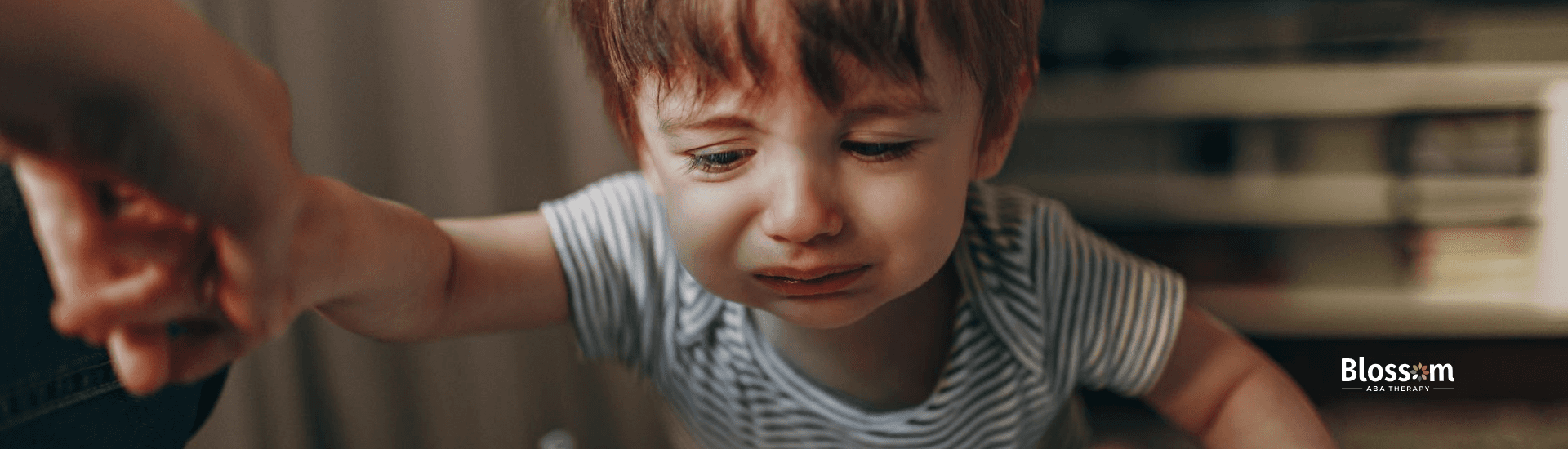 A crying toddler with autism reaching out with one hand, showing dissociation symptoms in Tennessee.