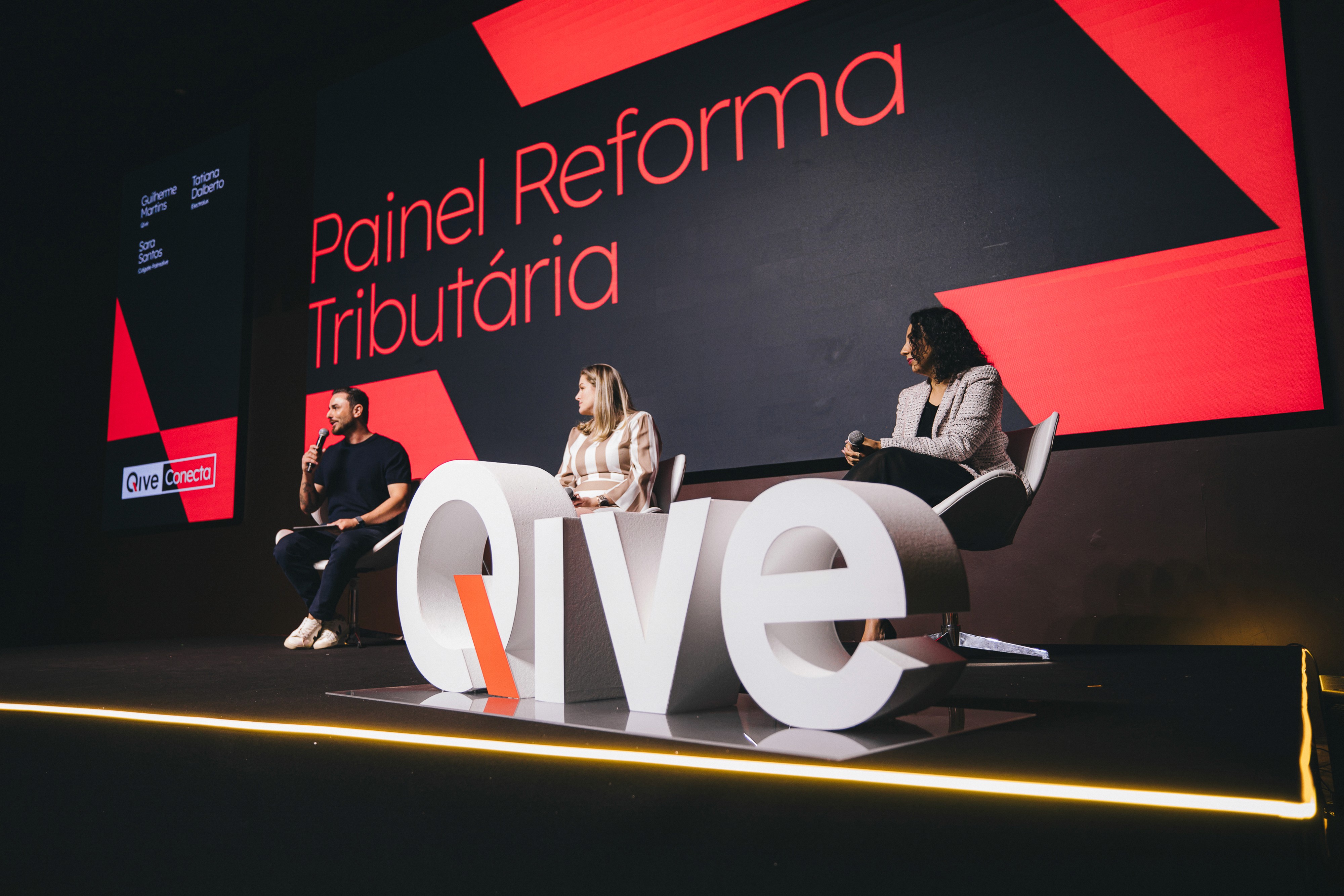 person discussing while standing in front of a large screen in front of people inside dim-lighted room