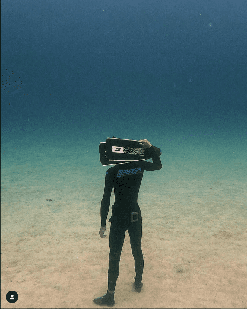 freediver meister holding fins standing underwater
