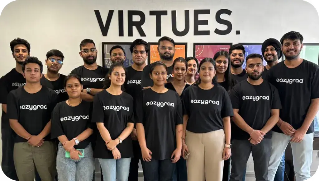 Group photo of individuals wearing black shirts, standing together in front of a "VIRTUES" wall sign.