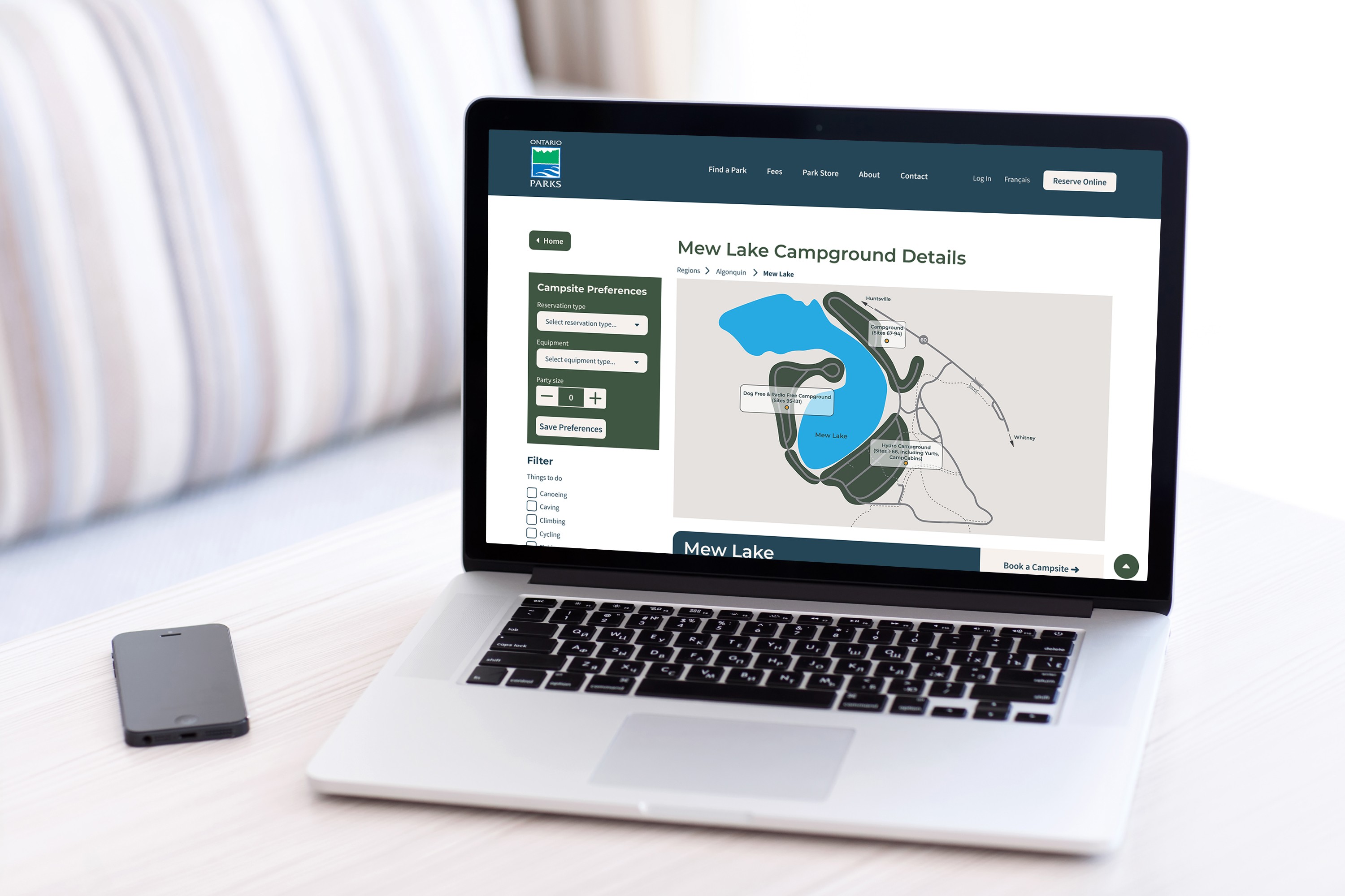 Gemini said A laptop displaying a detailed map and "Campsite Preferences" sidebar for Mew Lake Campground on the Ontario Parks website, showing the digital interface in a real-world setting.