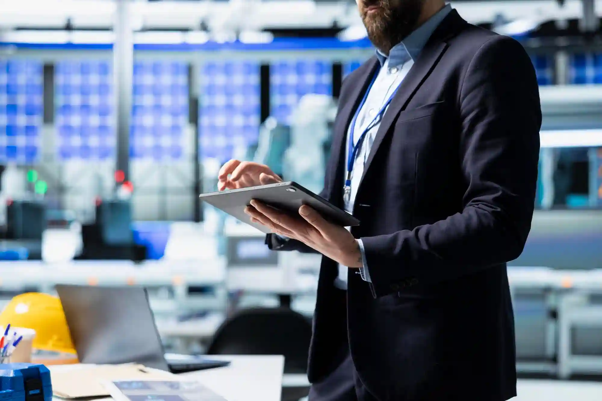 A professional using a tablet in a high-tech facility representing the operational management of algorithmic independence and compliance.