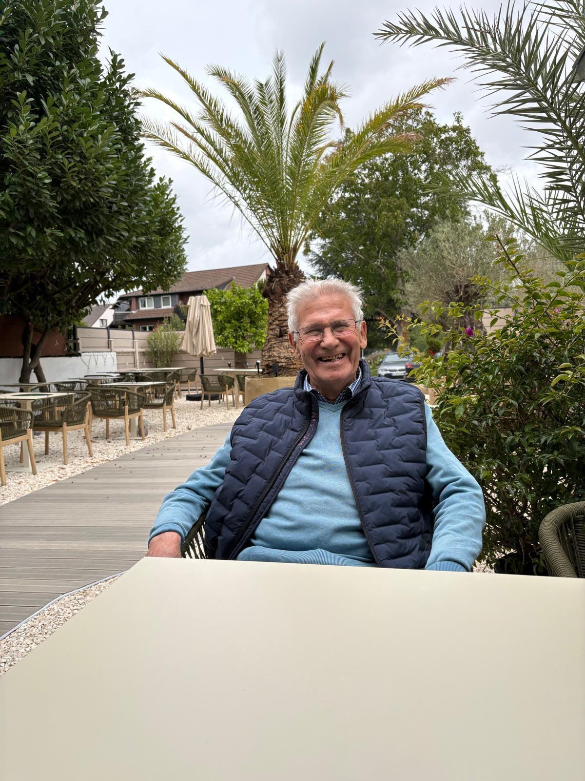 A person with curly hair sits at a desk, working on a laptop in a cozy, well-lit environment.