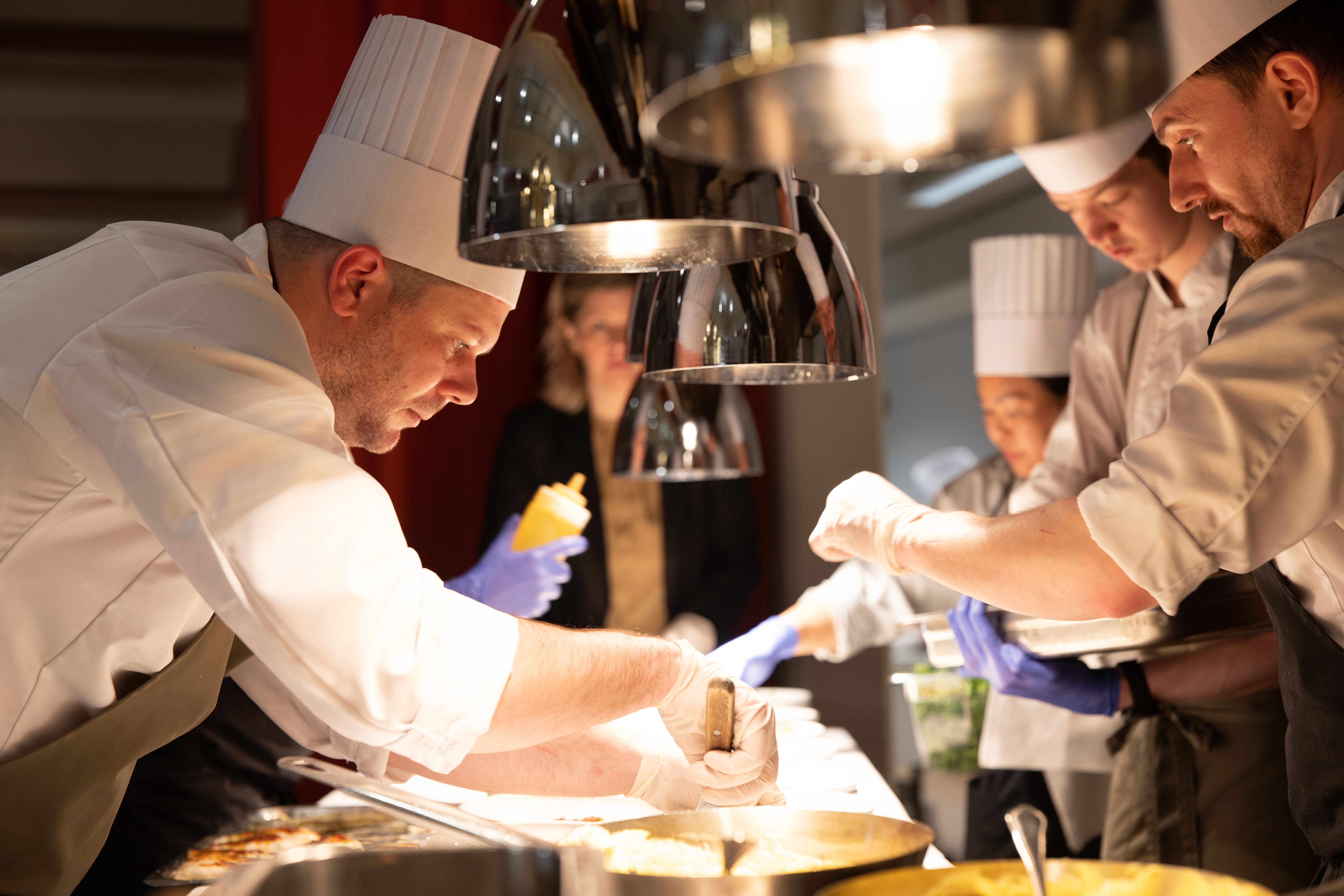 A beautifully set breakfast table next to a window with a scenic mountain view, featuring plates of assorted foods including sliced salmon, cheeses, boiled eggs, pastries, and glasses of orange juice.