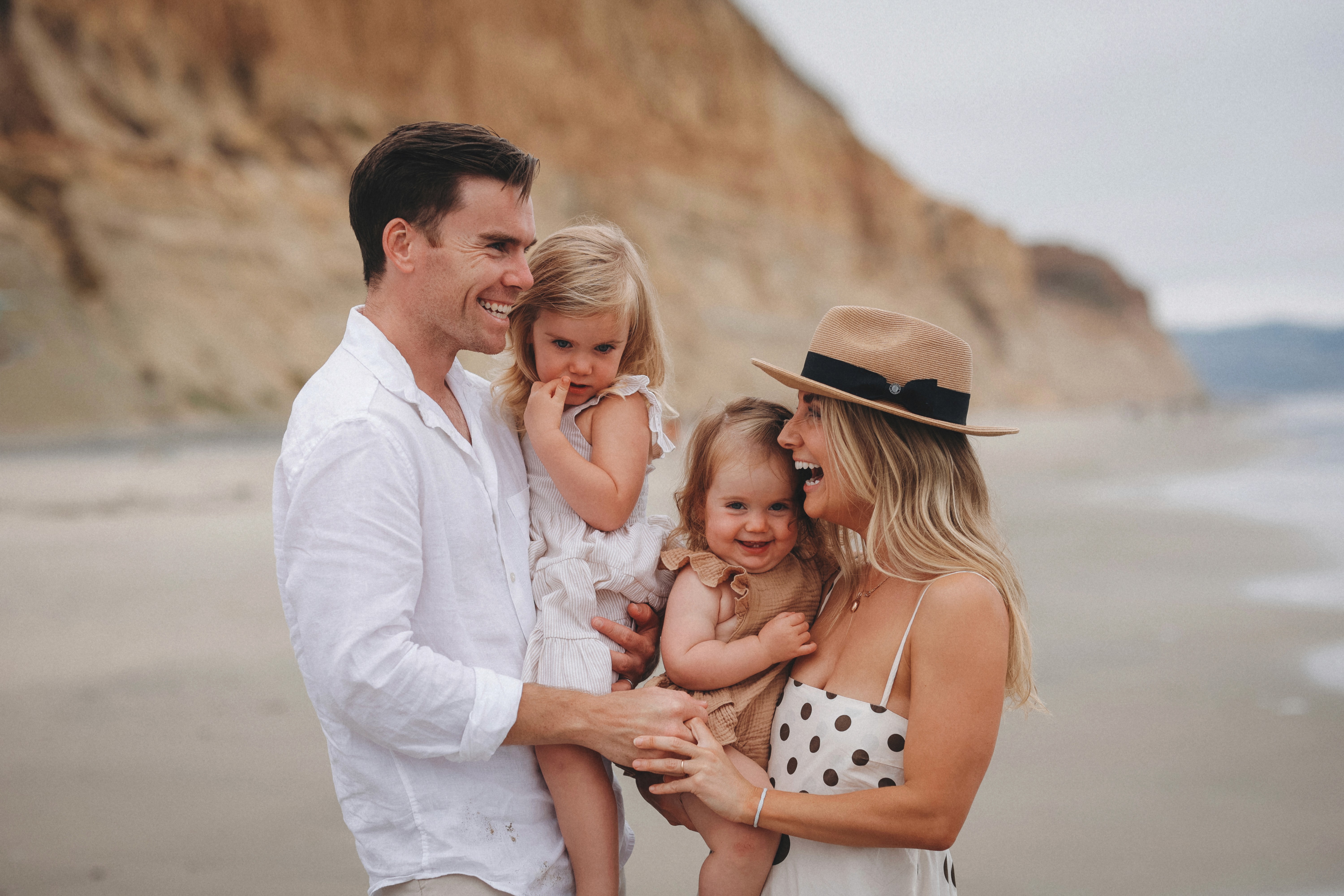 Family holding their children during a warm beach session at sunset in San Diego