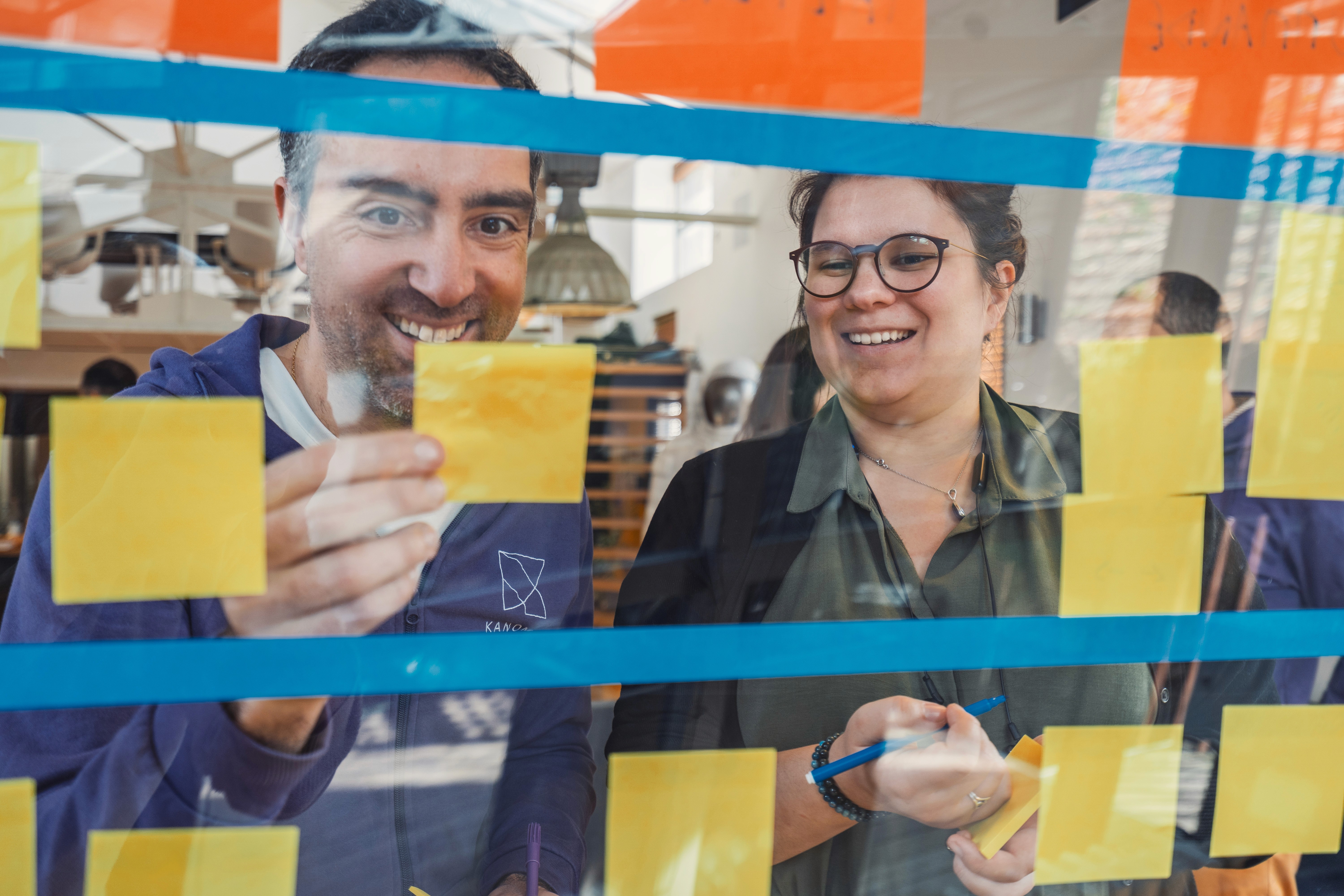 deux personnes sourient en lisant des mots sur des post its