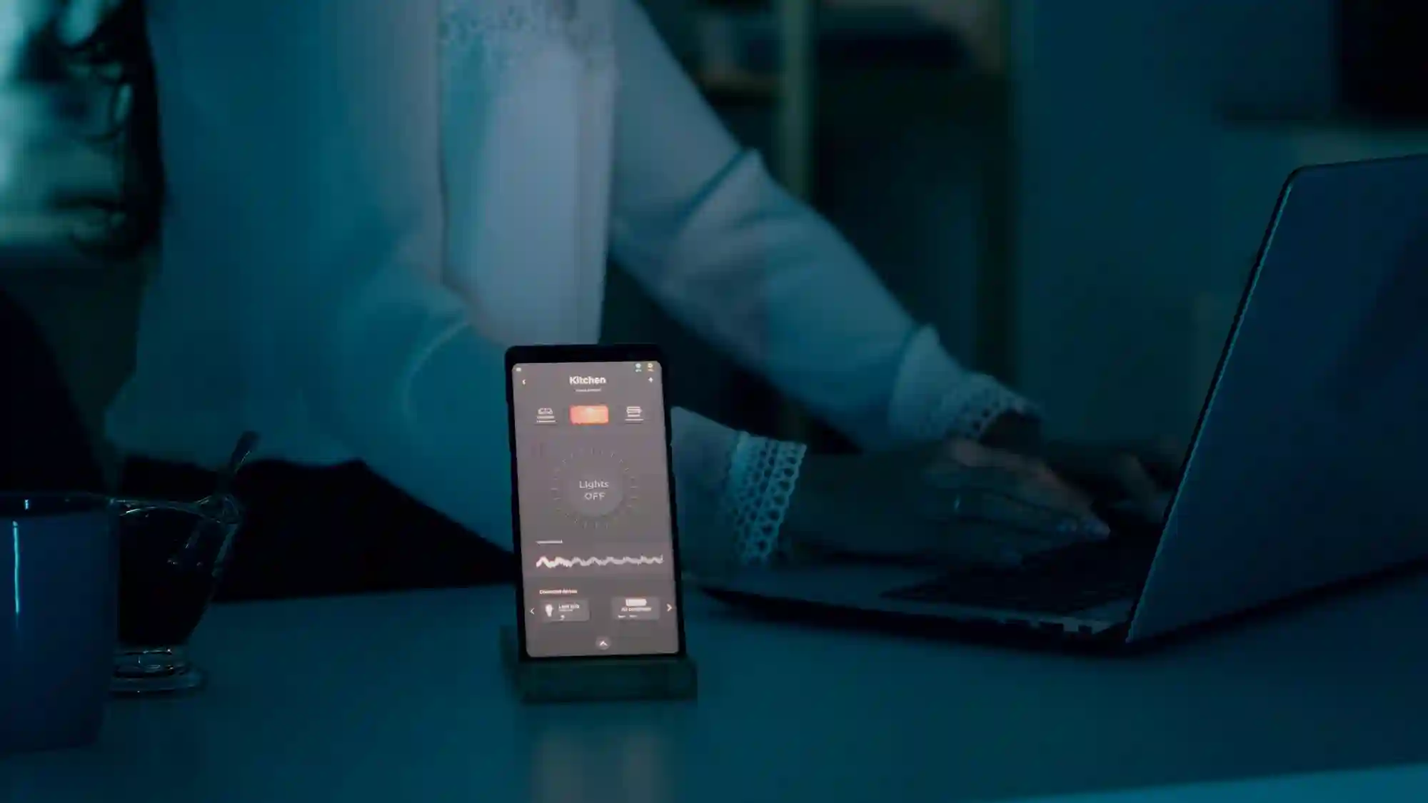 A smartphone displaying a dashboard next to a person working on a laptop, highlighting digital connectivity and productivity.