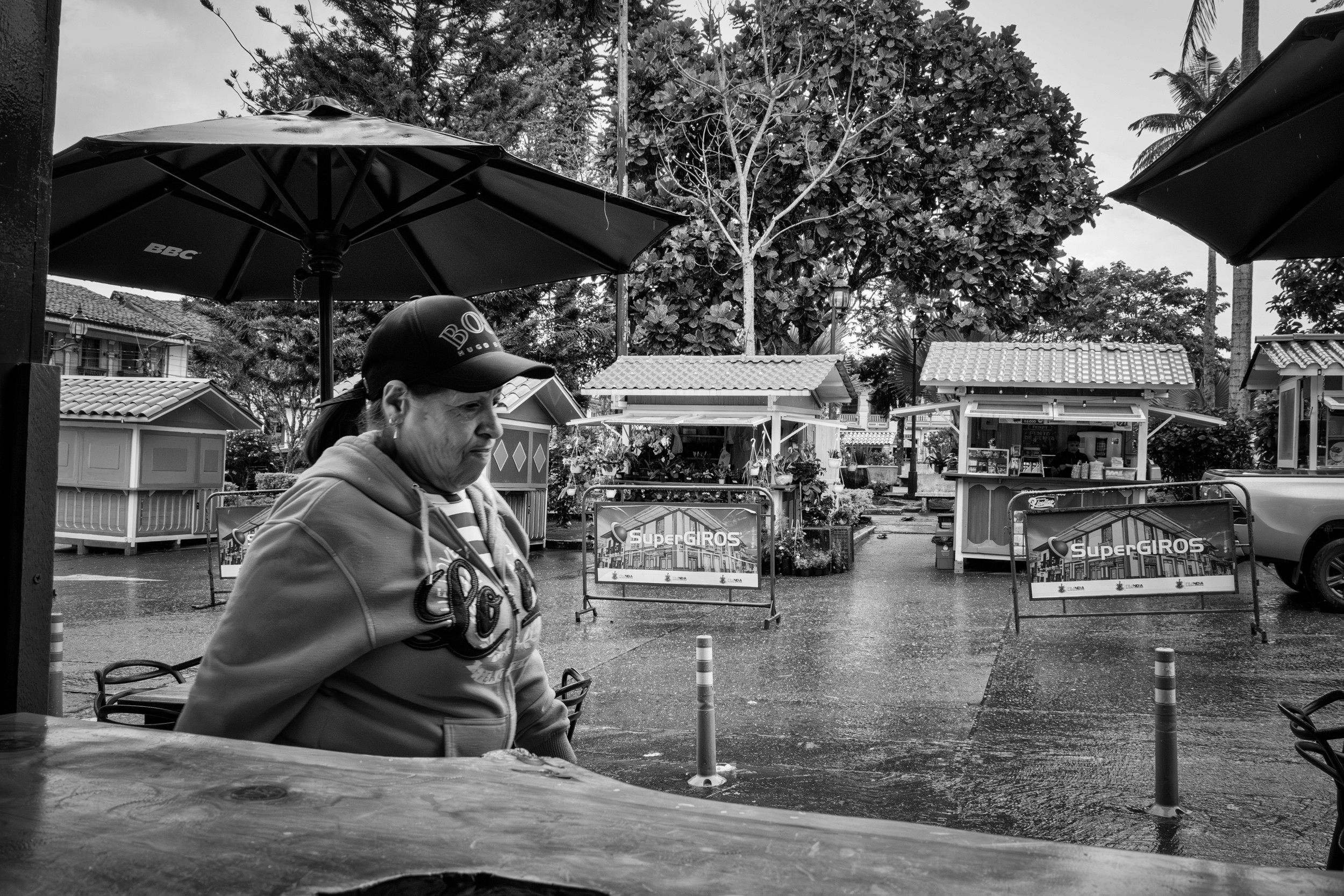 Rainy street scene with people passing by a bar window.